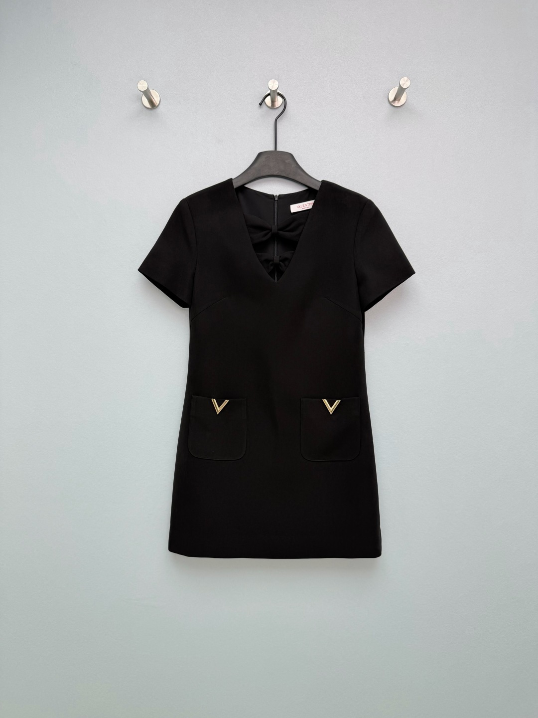 NO:780425,valentin*26 new black V-neck Loulong bow short dress, V-neck design modifies the neckline, transforms into a swan neck in seconds, visually makes the face smaller, sexy and high-end. The bow + hollow design on the chest, the front is dignified and elegant, stunning the audience with both sweetness and coolness. The brand's iconic golden V-shaped metal logo on the pocket, low-key highlights the brand identity, full of sophistication. Short straight A-line hem, covering the flesh and slimming, optimizing body proportions, making the legs appear taller, and not picky about the figure.  Classic pure black background + golden V logo, this little black dress is so beautiful that I am speechless!  Single color code 3 SML, Valentino-clothing, valentino, valentino, skirts,19860909valentin*26新款黑色V领楼龙蝴蝶结短款连衣裙 ,V领设计修饰颈线,秒变天鹅颈,视觉显脸小,性感又高级 胸前蝴蝶结+镂空设计,正面端庄优雅,惊艳全场甜酷兼具 口袋处品牌标志性金色V形金属标,低调彰显品牌身份,精致感拉满 短款直筒A字摆,遮肉显瘦,优化身材比例,显高显腿长,不挑身材 经典纯黑底色+金色V标,被这条小黑裙美到失语！单色3码SML,华伦天奴-服装,valentino,valentino,skirts,,Women's clothing