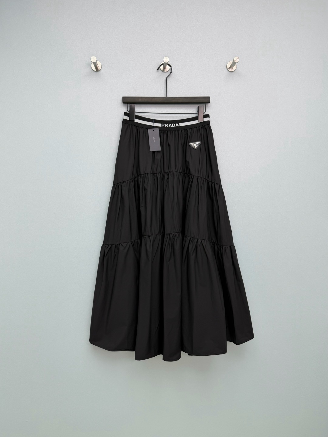 NO:781599,Prad*26 new tiered skirt with large hem, high waist letter waist + triangle logo, full of details, built-in noble filter. The tiered cake skirt hides a lot of flesh, pear-shaped sisters close their eyes, and the A-line silhouette is super slim. Both black and white are super versatile, the white is refreshing and age-reducing, and the black is slim and advanced. Paired with a T-shirt, it will become a sweet and cool girl. Paired with a shirt, it will instantly become a smart commuter style. It is a must-have in your wardrobe!  A versatile dress for a sweet and cool girl!  2 colors and 4 codes SMLXLB, Prada-clothing, prada, prada, skirts, shirts, tees, t-shirt,19860909Prad*26新款层叠式大摆半身裙 高腰字母腰头+三角logo,细节感直接拉满,自带贵气滤镜 层叠蛋糕裙摆巨藏肉,梨形身材姐妹闭眼冲,A字廓形超显瘦 黑白两色都超百搭,白的清爽减龄,黑的显瘦高级 搭配T恤是甜酷少女,搭衬衫又秒变干练通勤风,衣柜里必须安排！甜酷少女的百搭神裙！2色4码SMLXLB,普拉达-服装,prada,prada,skirts,shirts,tees，t-shirt,,Women's clothing