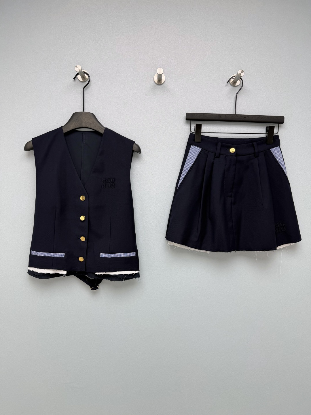 NO:784418,Miu Mi*26 new college style vest and skirt suit. The combination of vest and skirt is sweet and cool!  The vest has a V-neck single-breasted design, with metallic gold buttons, and an embroidered miu logo on the front. The blue plaid contrast stitching on the hem + raw edge lining design breaks the monotony. The lace design on the back can be adjusted to fit different body shapes.  The skirt has a high-waisted A-line silhouette, and the front also has the brand's embroidered logo. The side has blue plaid contrast stitching that echoes the waistcoat. The raw edge of the hem and the exposed lining design give it a casual college atmosphere. The skirt is neatly hidden and is very friendly to figures with wide hips and thick legs. This college-style suit directly welds the sense of gold on the body!  2 colors and 3 codes SMLSS, Miu Miu-clothing, miumiu, skirts,19860909Miu Mi*26新款学院风马甲半裙套装 马甲在短裙的组合 甜酷千金感天花板！马甲V领单排扣设计,搭配金属质感金色纽扣,正面带有刺绣miu 标识,下摆的蓝色格纹撞色拼接+毛边内衬设计,打破单调感,后背的系带设计可调节松紧,适配不同身形. 半裙高腰A字廓形,正面同样带有品牌刺绣标识,侧边蓝色格纹撞色拼接呼应马甲,下摆毛边+内衬外露设计,自带随性的学院氛围,裙型利落藏肉,对胯宽、腿粗的身材超友好. 这套学院风套装直接把千金感焊在身上！2色3码SMLSS,缪缪-服装,miumiu,skirts,,Women's clothing