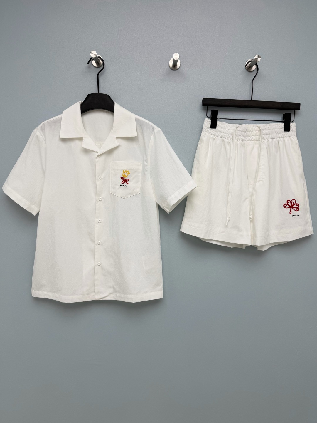 NO:785584,Prad*26 new embroidered short-sleeved shirt + shorts set, refreshing and relaxing in summer!  The yellow tulip embroidery on the shirt pocket + the red flower embroidery on the shorts, paired with the PD letter logo, are simple and recognizable. It adds a playful color highlight to the clean white suit, weakening the tough style of the brand and adding a gentle girlish feel. The Cuban collar shirt + elastic waist shorts, the version is loose and not flattering on the figure, hiding the flesh and making you look slim. The cotton blend fabric is breathable and comfortable, and you will not feel sweaty when wearing it in summer.  You don’t have to think about matching a set when you go out, it’s lazy and casual, and it’s perfect for vacations and shopping!  Single color size 3 SML, Prada-clothing, prada, prada, shorts, shirts, T-shirt,19860909Prad*26新款刺绣短袖衬衫+短裤套装 夏日清爽松弛感天花板！衬衫口袋的黄色郁金香刺绣+短裤上的红色花卉刺绣,搭配PD字母标识,简约又有辨识度,为干净的白套装增添了俏皮的色彩亮点,弱化了品牌的硬朗风格,多了几分温柔少女感.古巴领衬衫+松紧腰短裤,版型宽松不挑身材,藏肉又显瘦 棉混纺面料透气舒适,夏天穿完全不闷汗 一套出门不用想搭配,慵懒又随性,度假、逛街穿都超合适！单色3码SML,普拉达-服装,prada,prada,shorts,shirts,T-shirt,,Women's clothing