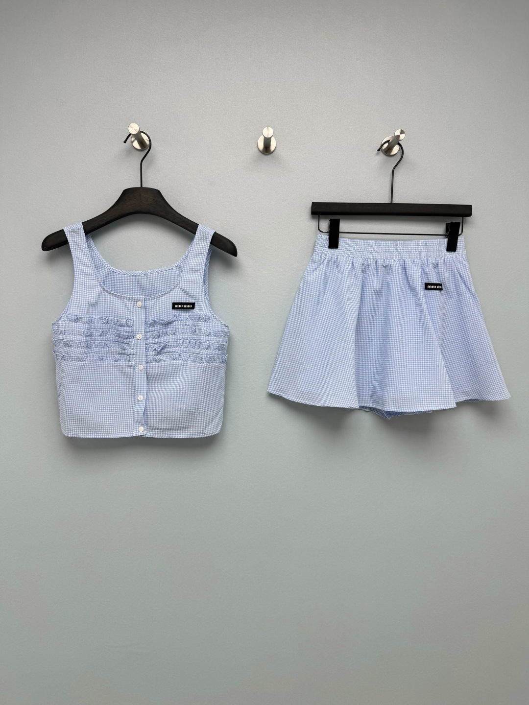 NO:823484,Miu Miu*26 new blue and white plaid pleated short suit. The top is a short square-neck sleeveless vest, with a single-breasted button on the front and a pleated design on the chest, which modifies the shoulder and neck lines while optimizing the body proportions. The bottom is high-waisted elastic waist short culottes, with anti-exposure lining, which is highly tolerant of the waist, abdomen and crotch lines, making it appear slimmer and hides the flesh. The Miu on the chest  The woven label is low-key and recognizable, and the brand texture can be seen in the details. It is unobtrusive but very noble. The blue and white plaid color scheme is fresh and gentle, with a college girl feel, and the chest pleat design balances sweetness and retro, and has a full age-reducing effect. Single color size 3 SML JA, Miu Miu-clothing, miumiu, skirts,19860909Miu Miu*26新款蓝白格纹褶皱短款套装,上衣为短款方领无袖背心,搭配前襟单排扣与胸前褶皱设计,修饰肩颈线条的同时优化身材比例；下装为高腰松紧腰短裙裤,自带防走光内衬,对腰腹、胯部线条包容度高,显瘦又藏肉,胸口的Miu 织标,低调又有辨识度,细节处见品牌质感,不张扬却很显贵.蓝白格纹配色清新温柔,自带学院少女感,搭配胸前褶皱设计,平衡了甜美与复古,减龄效果拉满.单色3码SML JA,缪缪-服装,miumiu,skirts,,Women's clothing
