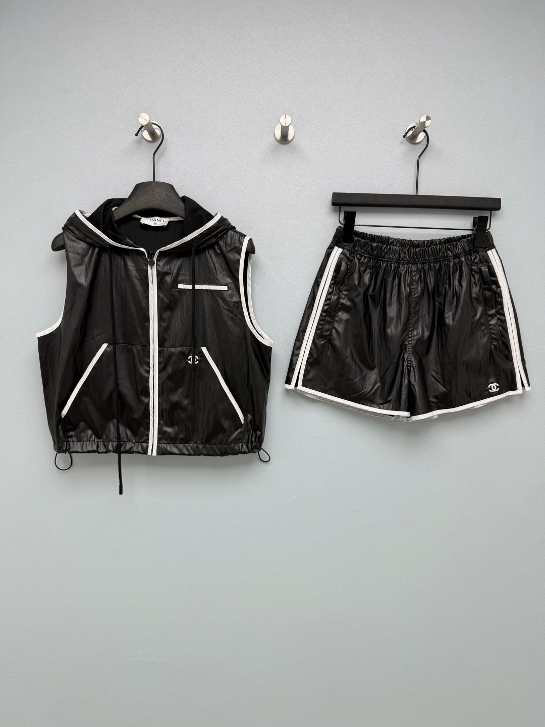 NO:825621,Chan*l26's new black and white sports and leisure suit is a combination of hooded sleeveless vest + elastic waist shorts. The vest is short + hem drawstring design, which can create a high waist line; the shorts are high-waisted A-line version, which can modify the width of the hips and thick legs. It is super friendly to the pear-shaped body, making it appear thinner and taller. The contrasting color of black and white brings out the atmosphere of high street hotties and light sports, which is a popular 'clean' at the moment.  'fit' 'American retro style' is a must-have item, which is easy to hold and has a cool and sweet sense of relaxation. It is made of lightweight nylon fabric with its own luster, which has a good drape and is not easy to deform. It has anti-wrinkle properties. It is refreshing and breathable in spring and summer. It can also be worn as a sun protection suit and is very easy to take care of. Double C embroidered logo is embellished, low-key and brand-recognizable; the suit design of hooded vest + shorts saves the worry of matching, and the whole upper body is directly released. Monochrome 3-code SML  L,Chanel-clothing,chanel,chanel,loro piana,shorts,hats,19860909Chan*l26新款黑白运动休闲套装 连帽无袖马甲+松紧腰短裤的组合,马甲是短款+下摆抽绳设计,能打造高腰线；短裤是高腰A字版型,能修饰胯宽、腿粗,对梨形身材超友好,显瘦又显高.黑白撞色自带高街辣妹与轻运动氛围,是当下热门的“clean fit”“美式复古风”刚需单品,轻松拿捏又酷又甜的松弛感.采用自带光泽感的轻薄尼龙面料,垂坠感好且不易变形,自带抗皱属性,春夏穿清爽透气,还能当防晒套装穿,打理也超方便.双C刺绣logo点缀,低调又有品牌辨识度；连帽马甲+短裤的套装设计,省去搭配烦恼,一整套上身直接出片.单色3码SML L,香奈儿-服装,chanel,chanel,loro piana,shorts,hats,,Women's clothing