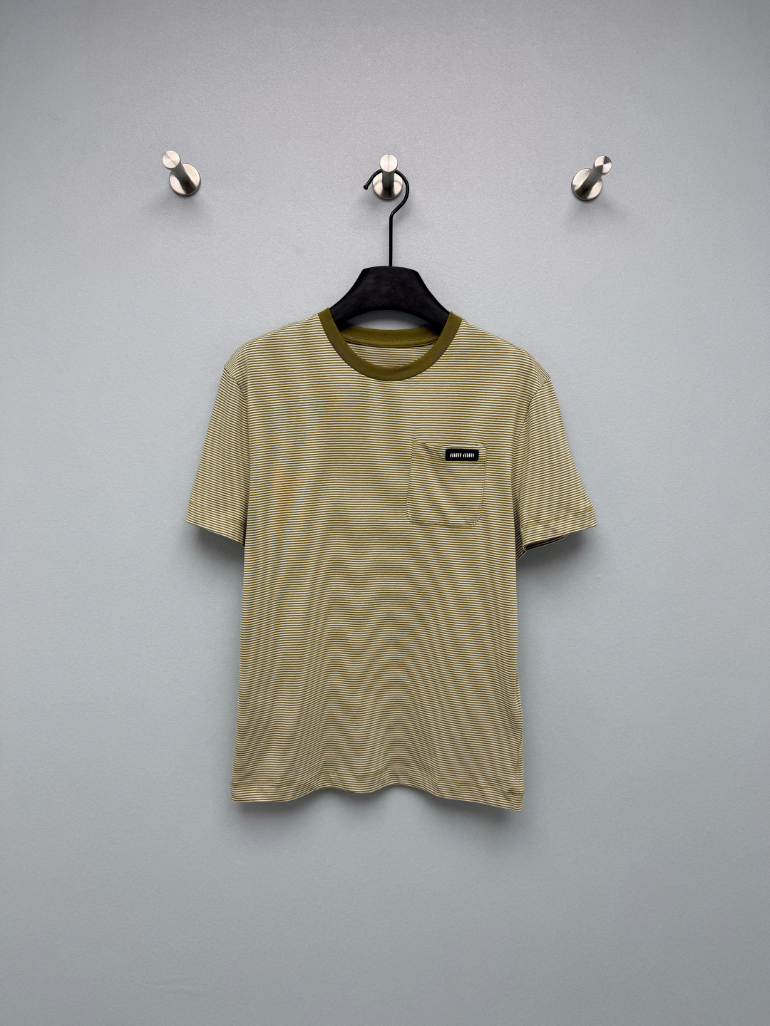 NO:828097,miu mi*26 new striped short-sleeved T-shirt. The chest pocket is matched with the miu woven label, which is the soul highlight of the entire T-shirt. It is low-key and has its own brand recognition, which instantly enhances the overall sophistication and breaks the monotony of the basic style. The low-saturated olive green + off-white stripes have a retro and relaxed feel, are not picky about skin colors, and are suitable for all styles and scenes, easily creating a complete retro relaxed look.  Single color size 3 SML, Miu Miu-clothing, miumiu, T-shirt, tees, t-shirt,19860909miu mi*26新款条纹短袖t恤 胸口口袋搭配miu织唛标,是整件T恤的灵魂亮点,低调又自带品牌辨识度,瞬间提升整体精致感,打破了基础款的单调感.低饱和的橄榄绿+米白条纹,自带复古松弛感,不挑肤色,适配所有风格和场景 轻松搭出一整套复古松弛感look 单色3码SML,缪缪-服装,miumiu,T-shirt,tees，t-shirt,,Women's clothing