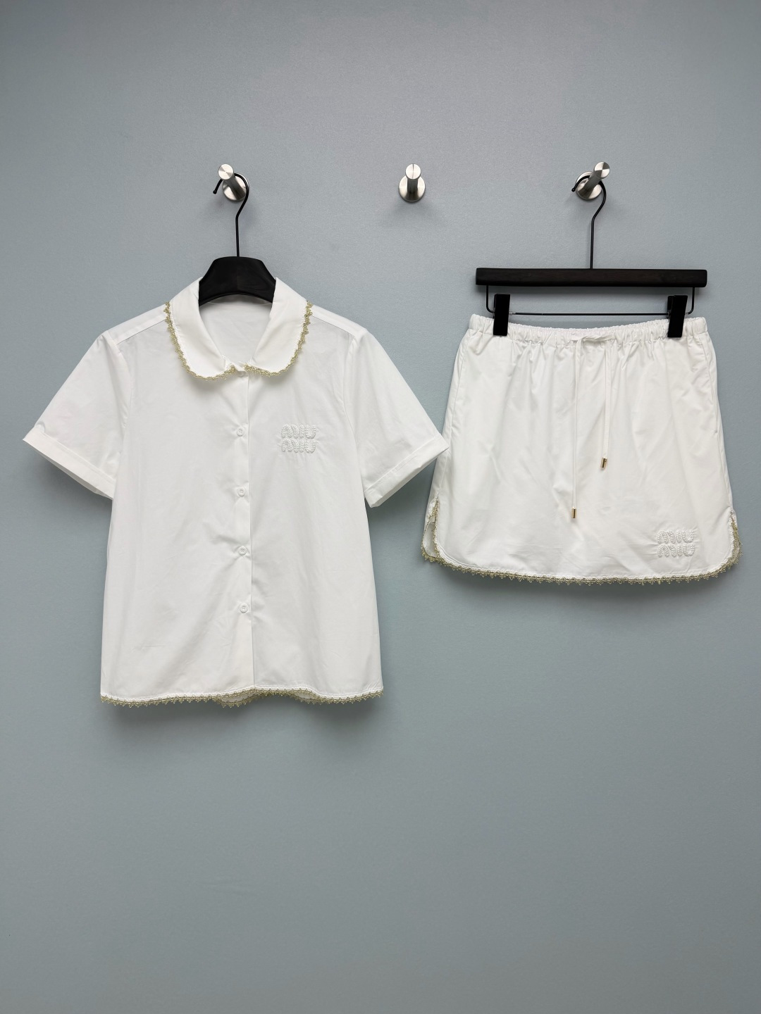 NO:830933,Miu Mi*26 new lace short-sleeved shirt + skirt suit  The shirt has a baby doll collar and a loose straight fit, which is friendly to all body types. The slightly loose design hides the flesh and makes you look slimmer, with a sense of laziness. The skirt has a high waist, an elastic waist, an A-line skirt, and a drawstring design that can be adjusted freely. It can not only raise the waistline and optimize the proportion, but also easily cover the crotch flesh. It is equipped with an anti-exposure design, making daily wear stress-free. The baby doll collar, shirt hem, and skirt hem are all embellished  The exquisite golden lace is gentle and noble, full of details. The three-dimensional woven embroidery logo on the chest and skirt is low-key and recognizable, highlighting the brand's tone. The drawstring of the skirt is matched with metal pendants, which is full of texture and easy to adjust the tightness. The whole outfit has a sweet girl college feel. Paired with white shoes, it will look like a energetic girl. Paired with Mary Jane shoes, it will become a gentle girl in an instant!  Single color code 3 SMLAW, Miu Miu-clothing, miumiu, mary jane, skirts, shirts, T-shirt,19860909Miu Mi*26新款蕾丝边短袖衬衫+半裙套装 衬衫娃娃领+宽松直筒版型,对各种身材都很友好,微宽松的设计藏肉又显瘦,自带慵懒感.半裙高腰松紧腰A字短裙,抽绳设计可自由调节松紧,既能拉高腰线优化比例,又能轻松遮住胯部肉肉,搭配防走光设计,日常穿无压力.娃娃领和衬衫下摆、半裙下摆都点缀了精致的金色蕾丝花边,温柔又显贵,细节感拉满.胸口和半裙上的立体编织刺绣logo,低调又有辨识度,凸显品牌调性.半裙的抽绳搭配金属坠饰,质感十足,同时方便调节松紧.整套搭配自带甜妹学院感,搭配小白鞋就是元气少女,搭配玛丽珍鞋则秒变温柔千金！单色3码SMLAW,缪缪-服装,miumiu,mary jane,skirts,shirts,T-shirt,,Women's clothing