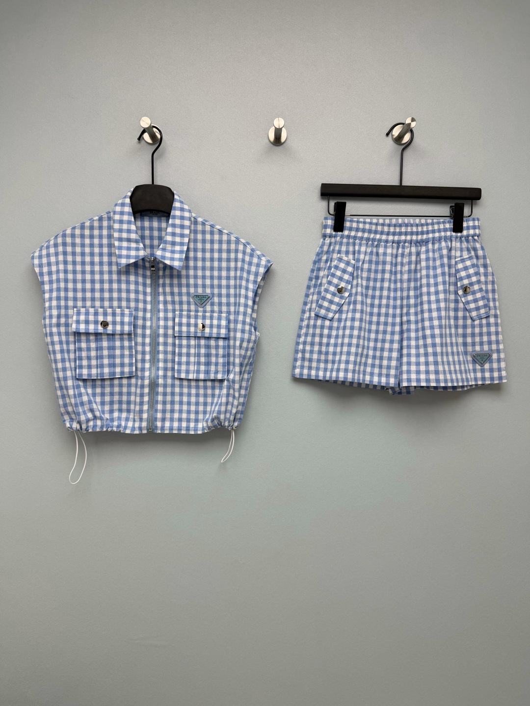 NO:859974,Prad*26 new plaid suit. The summer oxygen girl's natural outfit. The fresh blue and white plaid comes with a cooling filter. Wear it like a walking sea salt soda, and your energy will reduce your age!  The combination of a short sleeveless top + high-waisted shorts directly stretches the body proportions to the ceiling, and even a small person can wear it with long legs~ The drawstring design of the top can also adjust the length freely, and the cargo pockets are cool and practical. With the PD triangle logo, it will make you feel sweet and cool!  It is very suitable for daily wear, travel wear, and date wear. Pair it with white shoes and you will be a Korean oxygen girl. Pair it with canvas shoes and you will be an American retro hottie. It will look good no matter how you match it. Monochrome size 3 SML, Prada-clothing, prada, prada, shorts,19860909Prad*26新款格纹套装 夏日氧气少女的本命穿搭清新蓝白格纹自带降温滤镜,穿上就是行走的海盐汽水,元气又减龄！短款无袖上衣+高腰短裤的组合,直接把身材比例拉到天花板,小个子也能穿出大长腿~上衣的抽绳设计还能自由调节衣长,工装口袋又酷又实用,搭配PD三角标,甜酷千金感直接拉满！ 日常穿、出游穿、约会穿都超合适,随便配个小白鞋就是韩系氧气少女,配个帆布鞋就是美式复古辣妹,怎么搭都好看 单色3码SML,普拉达-服装,prada,prada,shorts,,Women's clothing