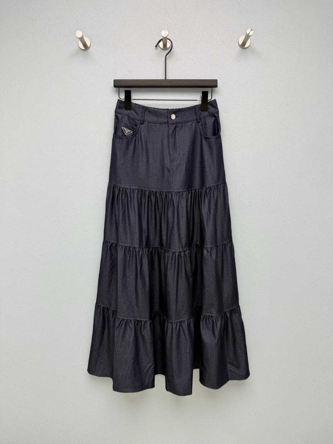 NO:860975,Prad*26’s new Tencel denim cake skirt combines the brand’s iconic triangle logo element with a romantic layered skirt to create an everyday item that has both a high-end feel and a relaxed feel!  The three-stage pleated cake skirt has a fluffy and drapey feel, which can not only modify the hip width and leg shape, but also present a smart and elegant effect as you walk, giving you a windy atmosphere when you walk. The imitation denim waist design, with button + pocket details, weakens the sweet feeling of the long skirt, and adds a bit of neat temperament of retro workwear, suitable for a variety of styles!  2 colors and 4 codes SMLXLB, Prada-clothing, prada, prada, skirts,19860909Prad*26新款天丝牛仔蛋糕半裙 将品牌标志性的三角标元素与浪漫的层叠裙摆结合,打造出兼具高级感与松弛感的日常单品！三段式抽褶蛋糕裙摆,自带蓬松感和垂坠感,既能修饰胯宽、腿型,又能随着走动呈现灵动飘逸的效果,走路带风氛围感拉满.仿牛仔的腰头设计,搭配纽扣+口袋细节,弱化了长裙的甜腻感,多了几分复古工装的利落气质,适配多种风格！2色4码SMLXLB,普拉达-服装,prada,prada,skirts,,Women's clothing
