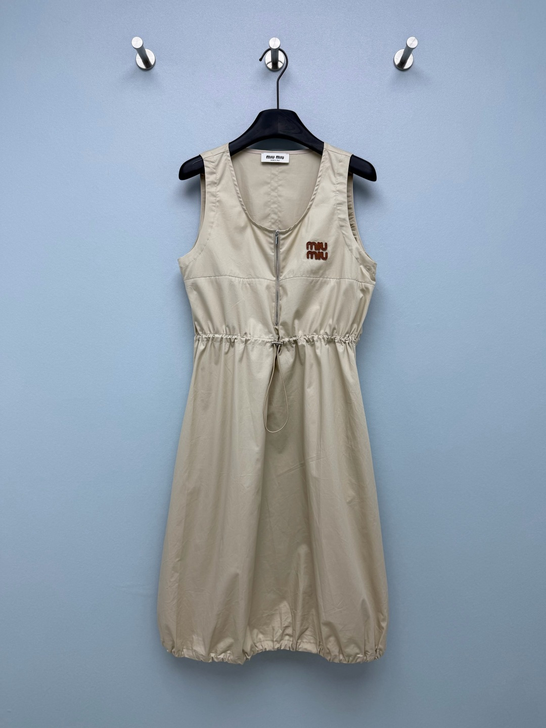 NO:862615,m home 26 new classic light khaki halterneck vest dress. The color comes with retro filters, a perfect miu style casual style item. The round neck sleeveless cut is refreshing and neat, suitable for spring and summer daily life, and it is excellent when layered with shirts/knitted vests. The half-open zipper design in the front makes it easy to put on and take off. The brand letters are embroidered on the chest, which is low-key and improves the sophistication. The drawstring at the waist can be freely tightened to optimize the body proportions and hide the fat on the waist and abdomen.  The hem of the skirt is closed with flower bud design, which is casual and not clinging to the legs; the small hollow slit on the back + invisible zipper carefully highlight the back line. The high-count cotton poplin fabric is stiff and anti-wrinkle, breathable and durable, and can be used for commuting, traveling and shopping. Solid color 3-code SML AP, Miumiu-clothing, miumiu, skirts, shirts,19860909m家 26新款经典浅卡其挂脖裙摆背心裙 配色自带复古滤镜,妥妥的miu系休闲风穿搭单品 圆领无袖剪裁清爽利落,适配春夏日常,叠穿衬衫/针织马甲都出彩 前中半开拉链设计,穿脱便捷；胸口植绒品牌字母刺绣,低调提升精致度 腰间抽绳可自由收束腰线,一键优化身材比例,藏腰腹赘肉 裙身下摆收口花苞设计,随性慵懒不贴腿；后背镂空小开叉+隐形拉链,小心机凸显后背线条 高支棉府绸面料挺括抗皱,透气耐穿,通勤、出游、逛街全能驾驭 单色3码SML AP,缪缪-服装,miumiu,skirts,shirts,,Women's clothing