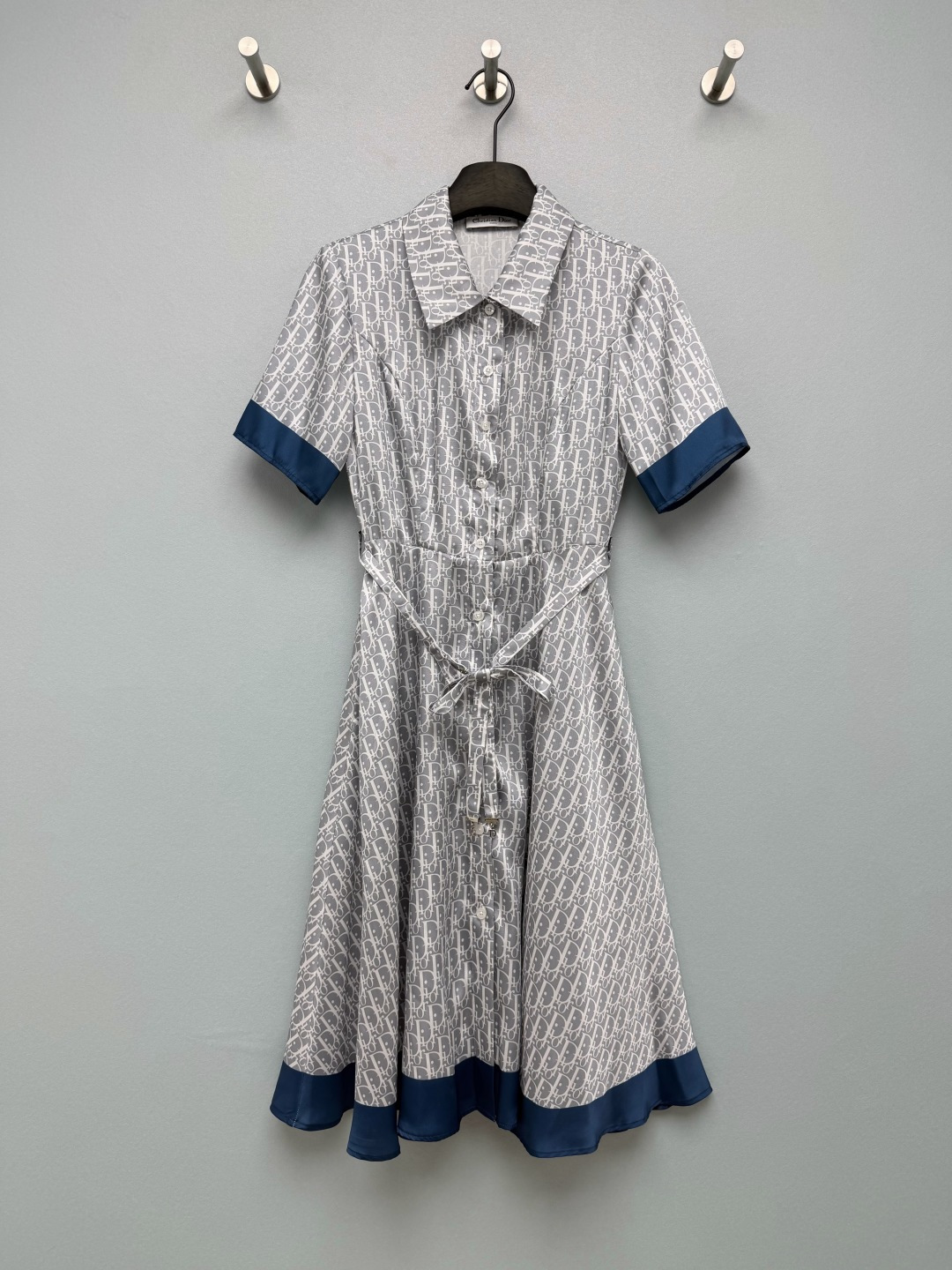 NO:865036,D*26 new classic Oblique old flower satin shirt dress  The whole body is printed with the iconic Oblique presbyopia dark pattern, a retro totem of the brand, which is a classic collection printing element. The light gray background is matched with gray letters, which is low-key and luxurious. The lapel + single-row fully buttoned shirt skirt version, short-sleeved cuffs and skirt are spliced with navy blue contrast satin  The breaded edge has clear layers; the waist comes with a lace of the same fabric, which can be tied freely to tighten the waist, easily creating a high-waist A-line skirt with a large hem, and optimizing the body proportions; the placket button is paired with an exclusive CD metal pendant accessory belt, which is full of brand details and highlights the sense of sophistication!  Single color size 3 SML, Dior-clothing, dior, skirts, shirts, T-shirt,19860909D*26新款经典Oblique老花缎面衬衫连衣裙 通体满印标志性Oblique老花暗纹,品牌复古图腾,是经典典藏印花元素,浅灰底色搭配灰色字母,低调轻奢.翻领+单排全开扣衬衫裙版型,短袖袖口、裙摆拼接藏青撞色缎面包边,层次分明；腰间附赠同面料系带,可自由系结收腰,轻松打造高腰线A字大摆裙型,优化身材比例；门襟纽扣搭配专属CD金属吊坠配饰腰带,品牌细节拉满,精致感突出！单色3码SML,迪奥-服装,dior,skirts,shirts,T-shirt,,Women's clothing