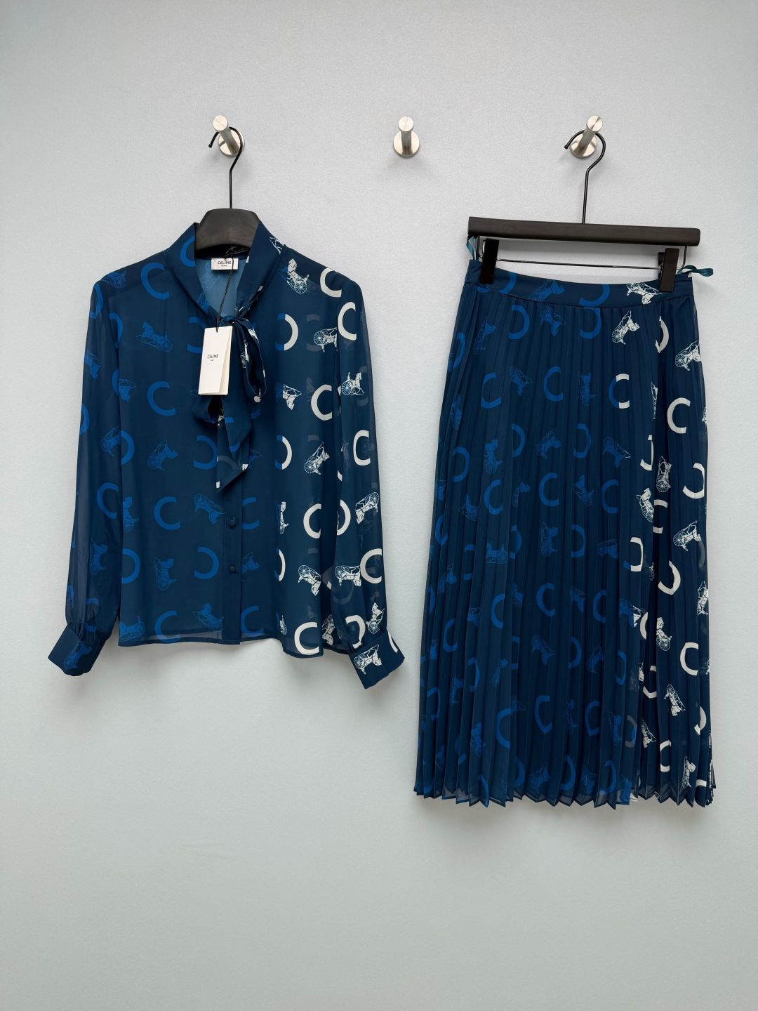NO:865044,CE*26 New Navy Carriage Print Ribbon Shirt Pleated Skirt Suit Stand-up collar with bow ribbons on the top, long sleeves with lantern cuffs, full placket with single row of concealed buttons of the same color, loose dropped shoulder short shirt style, neat waist reduction without weighing the body down; skirt with high waist elastic waist pleated mid-length skirt, high temperature shaping fine accordion pleats, skirt longer than the calf, hidden side zippers, modifying the width of the hips and thick legs.  Deep navy blue background color, white curved C logo + retro horse-drawn hand-painted all-over printing, classic mid-century style logo printing, retro light luxury, brand classic presbyopia elements, you don’t have to worry about matching when you go out in a complete set, you can get it for commuting and dating with one click, full of light luxury atmosphere. Monochrome 3-code SML, Celine-clothing, celine, skirts, shirts,19860909CE*26新款藏青马车印花飘带衬衫百褶半裙套装 上衣立领领口蝴蝶结飘带,长袖灯笼收口袖口,全开襟单排同色系暗扣,宽松落肩短款衬衣版型,利落收腰不压个子； 半裙高腰松紧腰百褶中长裙,高温定型细密风琴褶,裙长过小腿,侧边暗藏隐形侧拉链,修饰胯宽、腿粗. 深海藏青底色,白色弧形C标+复古马车手绘满印,经典中古风标识印花,复古轻奢,品牌经典老花元素,成套出门不用费心搭配,通勤约会一键搞定,轻奢氛围感拉满 单色3码SML,赛琳-服装,celine,skirts,shirts,,Women's clothing