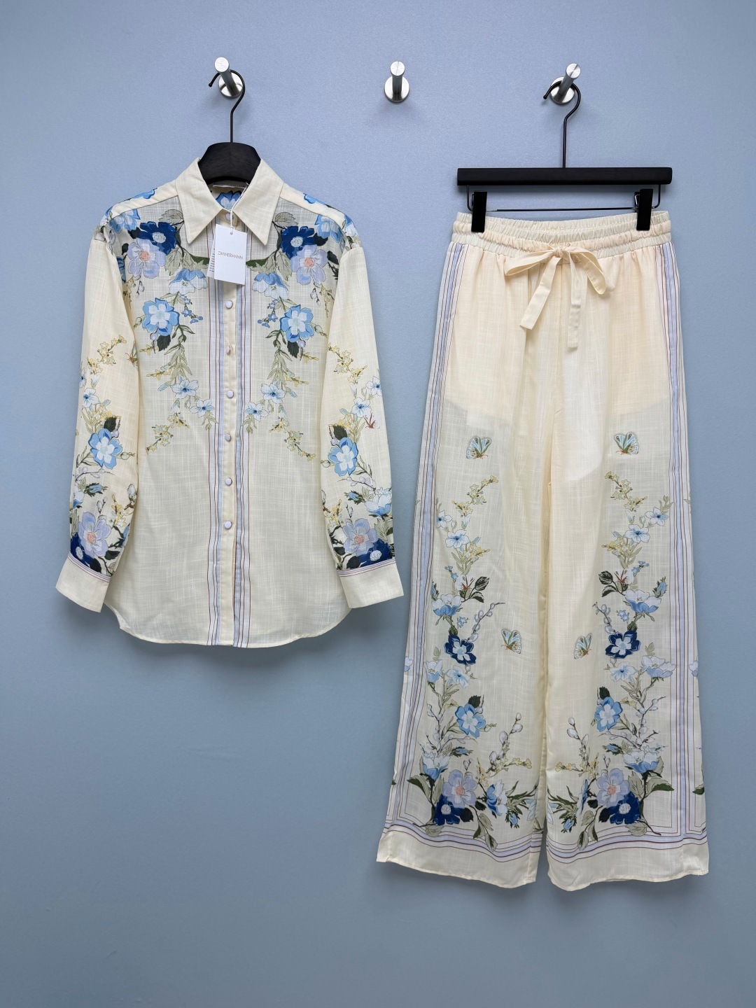 NO:865077,ZIMMERMA's latest blue flower butterfly print shirt wide-leg pants suit, a combination of shirt and wide-leg pants, hand-painted Chinese style blue jasmine + colorful butterfly positioning print on the bottom, flowers concentrated on both sides of the body and the middle seam of the trouser legs, with light brown pinstripe trim, fresh and retro, exclusive limited edition pattern!  The top is a classic lapel long-sleeved casual shirt with dropped shoulders, a single row of round buttons of the same color on the front, vertical thin contrasting stripes on both sides of the body, and blue flowers extending from the shoulder and neck to the cuffs. The mid-length hem can be tucked into the waist/worn outside; the bottoms are elastic drawstring high-waisted wide-leg trousers with an unrestricted waistband to suit various waistlines and pants.  The vertical strips on both sides of the body are hemmed in contrasting colors, and the trouser legs are positioned vertically with blue flowers and butterfly prints. The draped wide-leg tailoring modifies the leg shape and hides the hips to make you look slimmer. You don’t have to worry about matching it when you go out as a set. You can wear it separately to maximize the utilization. You can easily produce a single color in size 4 SMLXL when traveling. Zimmerman-clothing, shirts,19860909ZIMMERMA*新款蓝花蝴蝶印花衬衫阔腿裤套装 衬衣阔腿裤的组合 米杏底手绘国风蓝茉莉+彩蝶定位印花,花卉集中衣身两侧与裤腿中缝,搭配浅棕细条纹镶边,清新复古,独版限定花稿！上衣经典翻领长袖休闲衬衫,落肩宽松版型,前襟单排同色系圆扣,衣身两侧竖向细撞色条纹,蓝花从肩颈顺延至袖口,中长衣摆可塞腰/外穿；下装松紧抽绳高腰阔腿长裤,无束缚腰头适配各种腰围,裤身两侧竖条撞色包边,裤腿竖向定位蓝花+蝴蝶印花,垂坠阔腿剪裁修饰腿型、藏胯显瘦,成套出门不用费心搭配,拆分单穿利用率拉满,出游随手出片单色4码SMLXL,兹默曼-服装,shirts,,Women's clothing