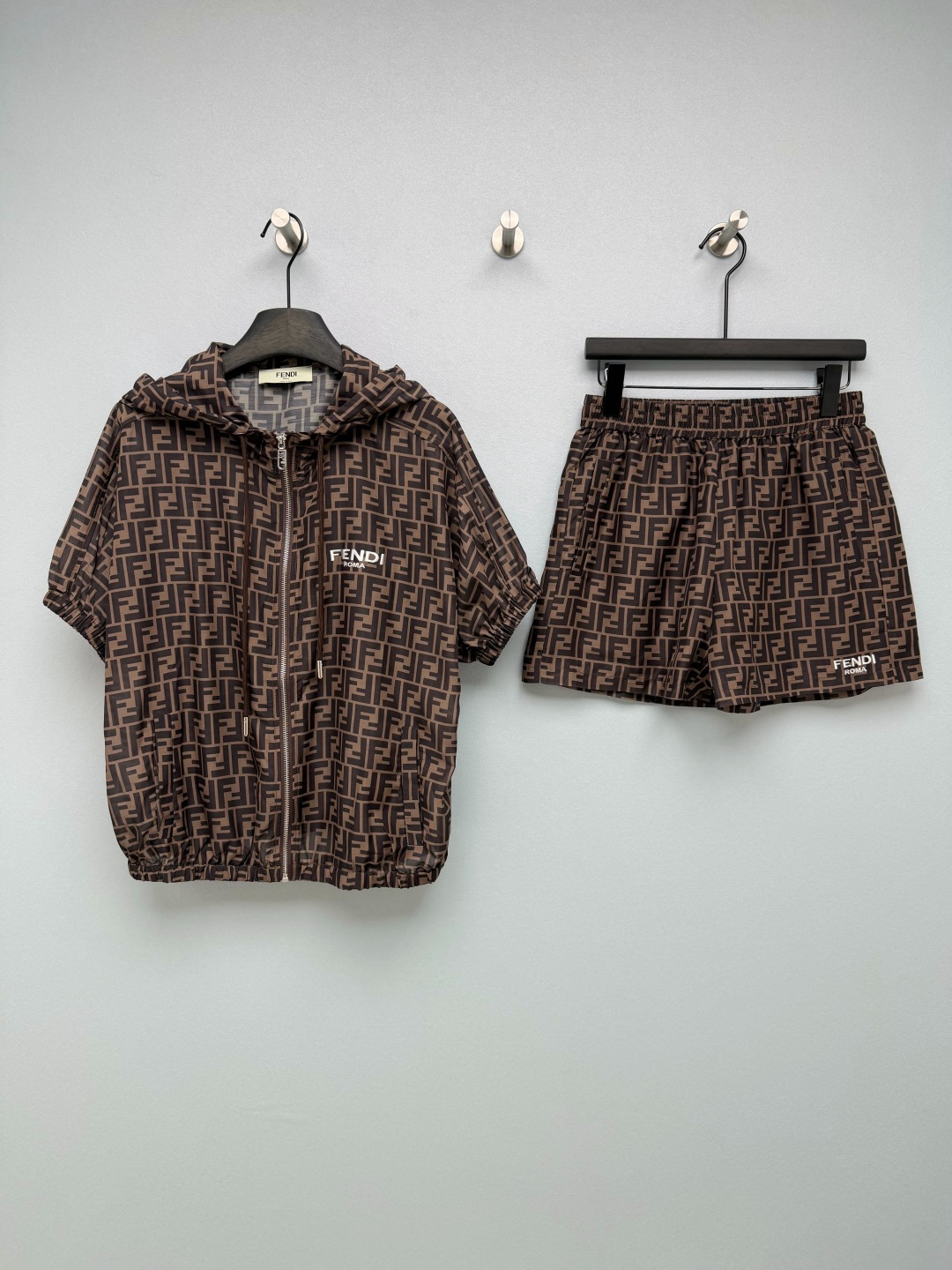 NO:865680,Fendi*26 new presbyopic sun protection suit, a combination of short-sleeved jacket and shorts, a summer outfit for lazy people!  The whole set adopts the classic double F presbyopia pattern, with a dark brown background and presbyopia of the same color. It is low-key and full of brand recognition. It has a retro and advanced sense of relaxation and is a classic element that will never go out of style.  The hooded jacket is made of light and breathable fabric, with both sun protection and windproof functions. It has a zipper closure + drawstring hem design, which can be adjusted freely. The loose silhouette is very tolerant to the body shape. The shorts of the same series are matched with an elastic waistband, which is comfortable and not tight, so lazy people can get it done in one set. The 'FEND*' on the jacket and shorts  ROMA' logo is a low-key way to highlight the brand identity and echo the presbyopia pattern; the coat's drawstrings, zippers and other hardware accessories are also consistent with the overall tone, and the details are full of sophistication. The whole outfit is lazy and casual, rich family style!  Solid color size 3 SML, Fendi-clothing, fendi, fendi, shorts, jackets & coats, T-shirt, hats,19860909Fendi*26新款老花防晒套装 短袖外套短裤的组合 夏日懒人穿搭！整套采用经典的双F老花图案,深棕底色搭配同色系老花,低调又充满品牌辨识度,自带复古高级的松弛感,是永不过时的经典元素. 连帽外套采用轻薄透气的面料,兼具防晒与防风功能,拉链开合+抽绳下摆设计,可自由调节版型,宽松廓形对身材包容度极高；同系列短裤搭配松紧腰头,舒适不勒肉,懒人出门一套就能搞定.外套和短裤上的“FEND* ROMA”标识,低调点明品牌身份,和老花图案形成呼应；外套的抽绳、拉链等五金配件,也和整体色调统一,细节处尽显精致感.整套穿是慵懒随性的富家千金风！单色3码SML,芬迪-服装,fendi,fendi,shorts,jackets & coats,T-shirt,hats,,Women's clothing