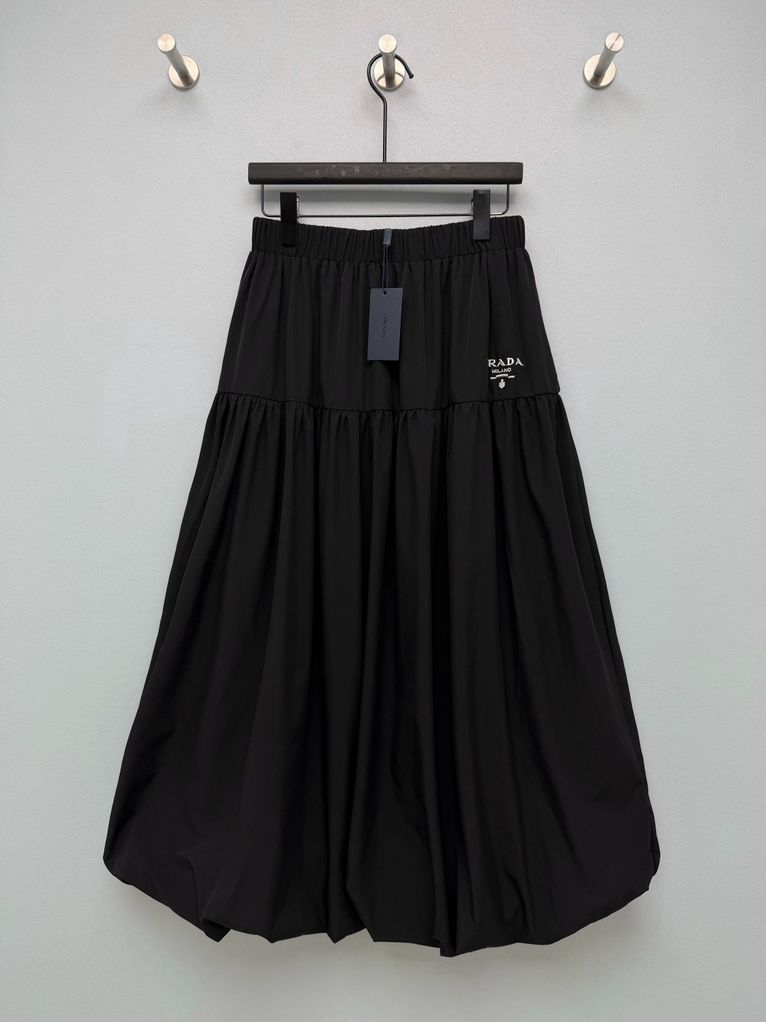 NO:933078,PRA* elastic waist layered bud skirt  The matte-textured blended fabric is both soft and skin-friendly and stiff, and can firmly support the fluffy shape of the skirt without clinging to the body. The elasticated high-waistband is comfortable and unrestricted, and accommodates a variety of waist and abdominal body shapes. It is easy to put on and take off, and the layered pleating and splicing technology creates a three-dimensional shape.  The lantern bud version modifies the lines of the crotch and legs, making walking smart and elegant. The fine embroidered letter logo on the side is simple and low-key, improving the overall texture. The pure white is refreshing and transparent, very suitable for spring and summer travel, and the classic black is calm and elegant, and can be used for daily commuting. Monochrome 4 code  SMLXL,Prada-clothing,prada,prada,skirts,19860909PRA*松紧腰分层花苞半身裙 哑光质感的混纺面料,兼顾柔软亲肤与挺括度,稳稳撑起裙摆蓬松的形态,不会软塌地贴在身上.弹力松紧高腰腰头,舒适无束缚,包容多种腰腹身形,穿脱方便,分层抽褶拼接工艺,塑造立体灯笼花苞版型,修饰胯部与腿部线条,行走灵动飘逸,侧边精细刺绣字母标识,简约低调,提升整体质感.纯净白清爽通透,很适合春夏出游,经典黑沉稳大气,通勤日常都可以驾驭.单色4码 SMLXL,普拉达-服装,prada,prada,skirts,,Women's clothing