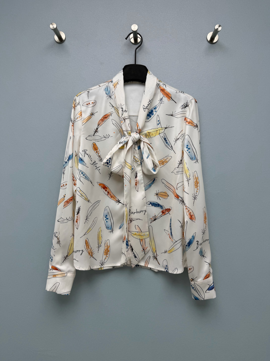 NO:946590,Bur* feather print ribbon satin shirt  Smooth and shiny satin material, with excellent drape, smooth touch, and soft light texture. The neckline is detachable with ribbon bows made of the same fabric. The knot design is elegant and gentle, and can be tied and detached to achieve two styles. Fully printed watercolor feather hand-painted prints, combined with handwriting art  Art font, rich and soft colors, full of artistic atmosphere. Front button closure, pearl texture buttons of the same color, exquisite and low-key; long sleeves match standard shirt cuffs, regular workmanship. The background color is clean off-white, the color is fresh, retro literary and artistic, suitable for daily commuting ~  Single color code 3 SML, Burberry-clothing, burberry, shirts,19860909Bur* 羽毛印花飘带缎面衬衫 顺滑有光泽的缎面材质,垂坠感出色,触感柔滑,自带柔光质感.领口可拆卸同面料飘带蝴蝶结,系结设计优雅温柔,可系可拆,实现两种穿搭风格.满印水彩羽毛手绘印花,搭配手写艺术字体,色彩丰富柔和,艺术氛围感十足.前襟暗扣开合,同色系珍珠质感纽扣,精致低调；长袖搭配标准衬衫袖口,做工规整.底色干净米白,配色清新,复古文艺,通勤日常都能驾驭～ 单色3码 SML,博柏利-服装,burberry,shirts,,Women's clothing