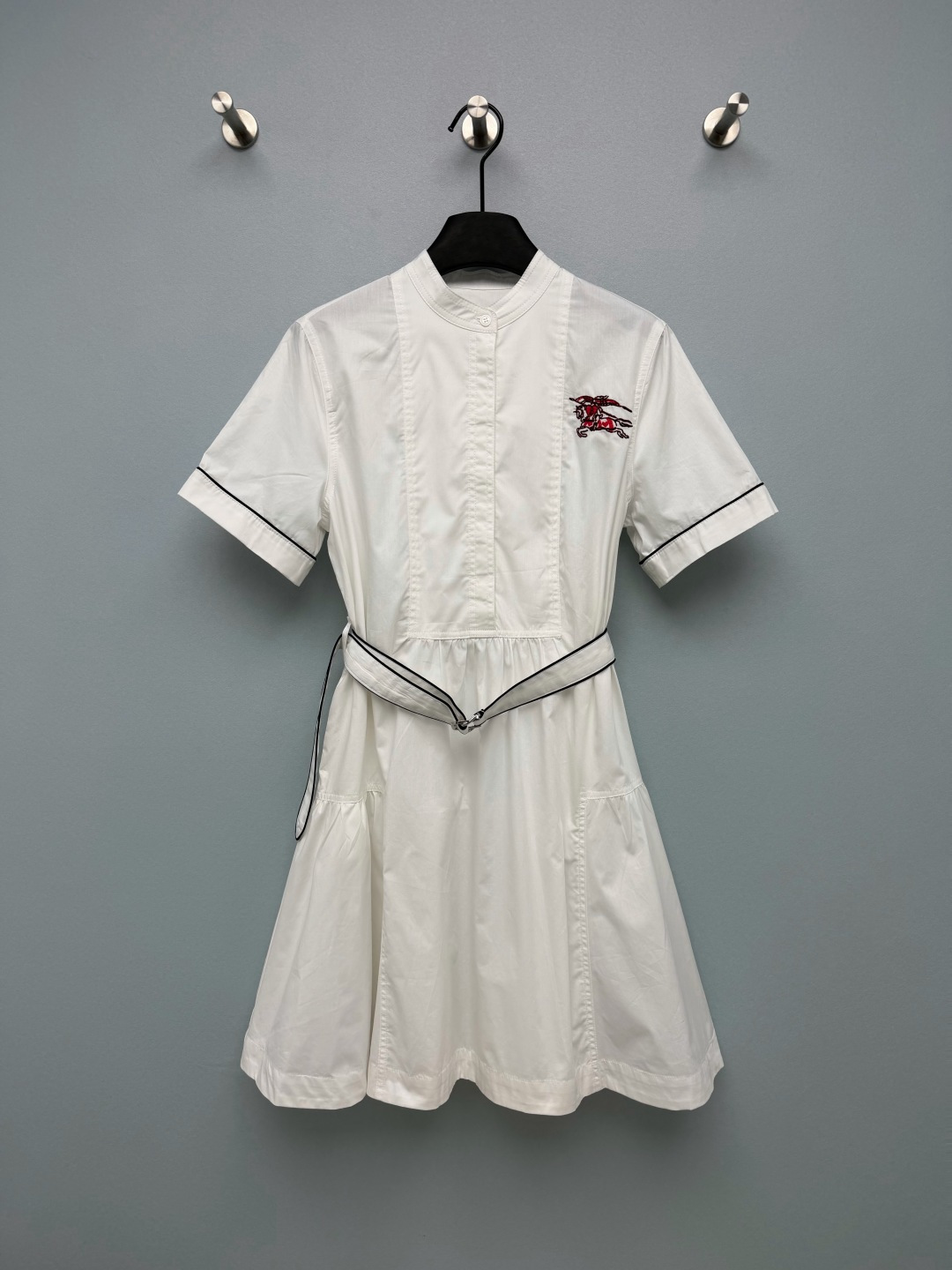 NO:946610,Stand collar white cotton short-sleeved dress  Crisp and breathable cotton fabric, with a refreshing texture and not easy to collapse, clean and white, easy to care for, breathable and comfortable to wear in summer. Simple small stand-up collar, half placket, brand engraved buttons, exquisite details. Red and black war horse embroidery logo on the chest, bright colors, high recognition. Cuffs,  The belt is embellished with black contrasting hemming, and the simple white skirt adds a sense of exquisite layering without being monotonous. The original contrasting belt can be adjusted to create a high waistline; the waist is pleated and spliced, and the A-line hem makes you walk elegantly and age-reducing. A clean and attractive little white skirt with high daily utilization rate.  Single color code 3 SML, Burberry-clothing, skirts, T-shirt,19860909立领白色棉料短袖连衣裙 挺括透气棉质面料,质感清爽不易软塌,干净洁白,打理方便,夏日穿着透气舒适.简约小立领,半开门襟,品牌刻印纽扣,细节精致.胸口红黑战马刺绣标识,色彩亮眼,辨识度高.袖口、腰带做黑色撞色包边点缀,简约白裙增加精致层次感,不会单调.原配撞色腰带,调节松紧塑造高腰线；腰部收褶拼接,A字伞摆,走动飘逸,减龄大方.干净耐看的小白裙,日常利用率很高 单色3码 SML,博柏利-服装,skirts,T-shirt,,Women's clothing