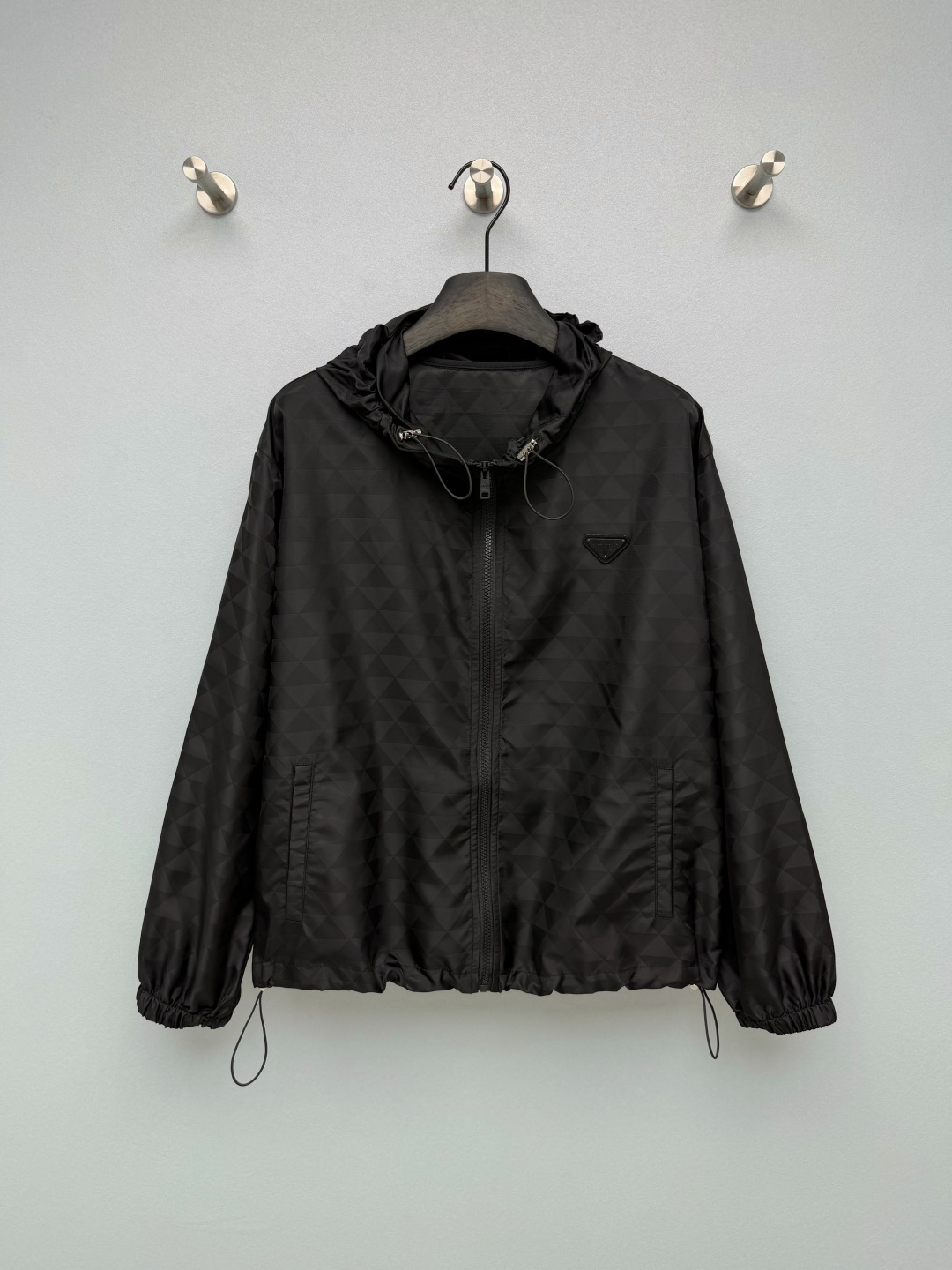 NO:946698,PRA* Dark Pattern Triangle Jacquard Hooded Jacket  Nylon jacquard fabric, full of low-key triangular dark texture, light and wind-resistant, the fabric has a matte texture, wear-resistant and easy to care for. The entire body of the garment is hidden with triangular geometric jacquard, low-key and unobtrusive, and has a sense of high-end texture if you look closely. The classic metal triangle logo on the chest is the brand's iconic logo, making it highly recognizable.  Hooded design, the hood is equipped with a brand-engraved metal adjustment buckle, with exquisite details. The whole garment is zippered, making it easy to put on and take off. Practical pockets on both sides combine beauty and practicality. The cuffs and hem can be tightened with drawstrings, which can be used to create a loose and casual effect of dropped shoulders, or tightened to create a neat and short style. Low-key and high-end  Black light luxury coat ceiling!  Single color size 3 SML, Prada-clothing, prada, prada, jackets & coats, hats,19860909PRA*暗纹三角提花连帽冲锋外套 尼龙提花面料,满幅低调三角暗纹肌理,轻薄抗风,面料自带哑光质感,耐磨易打理.整件衣身暗藏三角几何提花,低调不张扬,细看富有高级肌理感.胸前经典金属三角标,品牌标志性标识,辨识度拉满.连帽设计,帽口配有品牌刻印金属调节扣,细节精致.全衣拉链开合,穿脱便捷；两侧实用插袋,兼顾美观与实用性.袖口与下摆均可抽绳收紧,可做宽松落肩休闲效果,也可收紧打造利落短款效果.低调高级 黑系轻奢外套天花板！ 单色3码SML,普拉达-服装,prada,prada,jackets & coats,hats,,Women's clothing