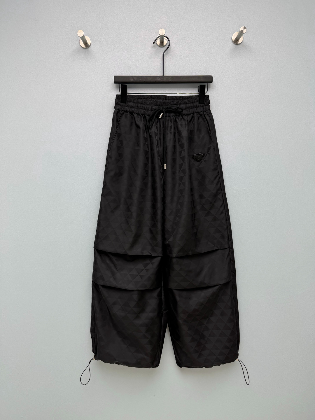NO:946688,PRA* dark pattern triangle jacquard wide-leg paratrooper pants  Nylon jacquard fabric, all-over triangular dark pattern jacquard texture, matte texture, anti-wrinkle and wear-resistant, the fabric is crisp and stylish, not easy to collapse and deform. The same color triangular dark pattern jacquard is low-key and restrained, showing exquisite texture under light and shadow, unobtrusive but highly recognizable. The classic metal triangle nameplate on the side of the trousers is the brand's iconic element. The elastic waist is matched with brand engraving  The printed metal drawstring buckle makes it easy to put on and take off, and the waist elasticity can be adjusted freely. The paratrooper pleat design on the trouser body adds a three-dimensional sense of layering to the trousers; practical pockets on both sides. The trouser legs are equipped with a drawstring, which can be relaxed and wide-legged when released, and can be tightened to become a leggings workwear style; it can be worn with jackets and skirts of the same series. Wear it as a pair, this paratrooper trousers is full of practicality  Solid color size 3 SML,Prada-clothing,prada,prada,skirts,jackets & coats,19860909PRA*暗纹三角提花阔腿伞兵裤 尼龙提花面料,满幅三角暗纹提花肌理,哑光质感,抗皱耐磨,面料挺括有型,不易软塌变形.全身同色三角暗纹提花,低调内敛,光影下显现精致肌理,不张扬却辨识度很高.裤身侧边经典金属三角铭牌,品牌标志性元素.松紧腰搭配品牌刻印金属抽绳扣,穿脱方便,可自由调节腰部松紧.裤身伞兵褶裥设计,增加裤子立体层次感；两侧实用插袋.裤脚自带抽绳,放开是松弛阔腿效果,收紧秒变束脚工装风；可与同系列外套、半裙组成成套穿搭.一裤两穿,这条伞兵裤实用性拉满 单色3码 SML,普拉达-服装,prada,prada,skirts,jackets & coats,,Women's clothing