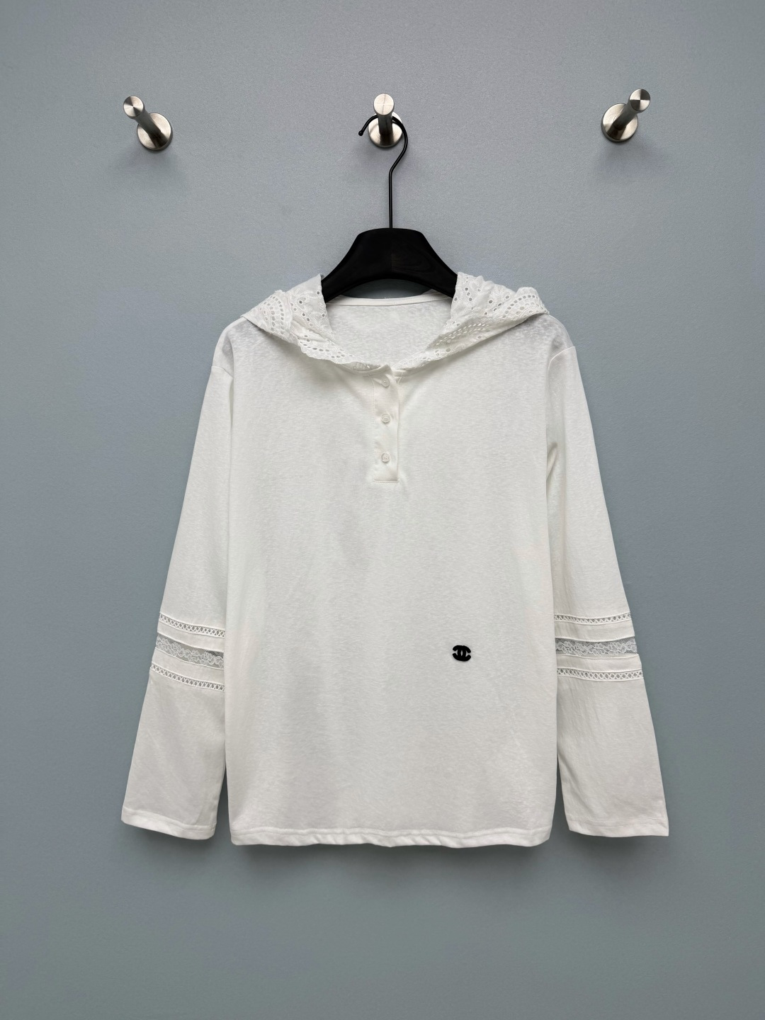 NO:946735,CHA* Lace Hooded Henley Neck Long Sleeve Top  Light and breathable knitted fabric, soft and skin-friendly, fine texture, refreshing and comfortable upper body, and breathable. The edge of the hat is spliced with hollow lace, which is delicate and soft, different from ordinary hoodies, and full of atmosphere. The half-open design of three Henry shell buttons on the front is easy to put on and take off, and the opening and closing of the neckline can be adjusted. Double  The sleeves are multi-layered with lace splicing, and the hollow lace is rich in layers, adding a romantic and sweet sense of detail. The body has a small black double C embroidered logo on the chest, which is low-key, luxurious and unobtrusive. The clean off-white background is gentle and refreshing, suitable for a variety of bottoms. The sweet but not greasy lace hoodie perfectly blends gentleness and leisure.  Single color size 3 SML, Chanel-clothing, chanel,hats,19860909CHA*蕾丝连帽亨利领长袖上衣 轻薄透气针织面料,手感柔软亲肤,肌理细腻,上身清爽舒适,兼具透气性.帽子边缘拼接镂空蕾丝花边,精致柔美,区别普通连帽衫,氛围感拉满.前襟亨利三粒贝壳扣半开设计,穿脱方便,可调节领口开合度.双袖多层蕾丝拼接,镂空花边层次丰富,增加浪漫甜美的细节感.衣身胸口小巧黑色双C刺绣标识,低调轻奢,不张扬.干净米白底色,温柔清爽,适配多种下装.甜而不腻的蕾丝连帽衫,把温柔和休闲融合得恰到好处 单色3码 SML,香奈儿-服装,chanel,hats,,Women's clothing