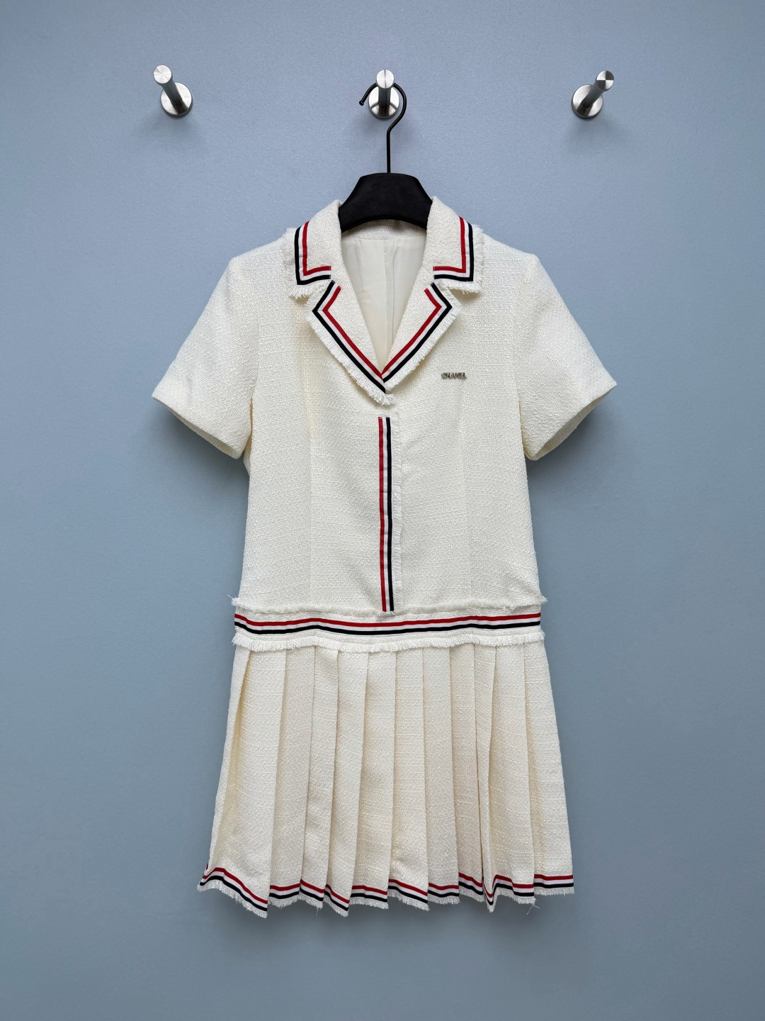 NO:946800,CHA* preppy Xiaoxiang pleated dress  Tweed woven fabric has a full texture, a crisp and stylish texture, and is fully lined inside, making it comfortable to wear without digging into the skin. The raw edge tassel suit lapels are edged with red, white, and black webbing, with classic college contrasting colors, and are highly recognizable. The placket continues to be decorated with three-color webbing, and the metal three-dimensional brand logo on the chest highlights the brand details in a low-key manner. The raw-edged tassel splicing at the waist and the transition of the three-color webbing divide the proportions of the upper and lower bodies and optimize the body.  Material. Pleated skirt at the hem, with the same three-color webbing hem. The pleats are neat and three-dimensional and not easy to collapse. The short-sleeved suit has a small lapel version, the upper body is cut to fit, the waist is split and spliced, and the lower part is connected to a pleated short skirt. The off-white is gentle and clean, and the black is classic and slimming. The two colors are suitable for different dressing needs. The A-line pleated version modifies the crotch and thighs, and the short skirt length is tall and neat, giving it both a girlish look and a sophisticated ladylike temperament.  Two-color code 3 SML, Chanel-clothing, chanel, skirts, T-shirt, business suit,19860909CHA* 学院风小香百褶连衣裙 粗花呢编织面料,肌理感饱满,质感挺括有型,内里全里衬,穿着舒适不扎肤.毛边流苏西装翻领,搭配红、白、黑三色织带包边,经典学院撞色,辨识度很高.门襟处延续三色织带装饰,胸口金属立体品牌标识,低调彰显品牌细节.腰节毛边流苏拼接+三色织带过渡,分割上下身比例,优化身材.下摆百褶裙身,裙边同样三色织带锁边,褶子工整立体,不易塌陷.短袖西装小翻领版型,上身为收剪合身剪裁,腰部分割拼接,下接百褶短裙摆.米白温柔干净,黑色经典显瘦,两种配色适配不同穿搭需求.A字百褶版型修饰胯部与大腿,短款裙长显高利落,兼具少女感与精致名媛气质. 双色3码 SML,香奈儿-服装,chanel,skirts,T-shirt,business suit,,Women's clothing