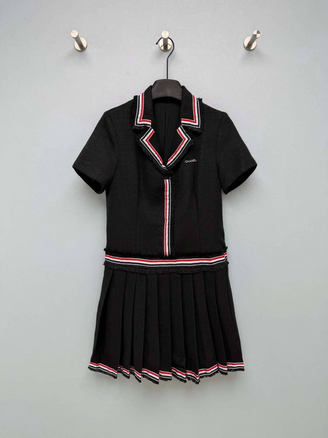 NO:946781,CHA* preppy Xiaoxiang pleated dress  Tweed woven fabric has a full texture, a crisp and stylish texture, and is fully lined inside, making it comfortable to wear without digging into the skin. The raw edge tassel suit lapels are edged with red, white, and black webbing, with classic college contrasting colors, and are highly recognizable. The placket continues to be decorated with three-color webbing, and the metal three-dimensional brand logo on the chest highlights the brand details in a low-key manner. The raw-edged tassel splicing at the waist and the transition of the three-color webbing divide the proportions of the upper and lower bodies and optimize the body.  Material. Pleated skirt at the hem, with the same three-color webbing hem. The pleats are neat and three-dimensional and not easy to collapse. The short-sleeved suit has a small lapel version, the upper body is cut to fit, the waist is split and spliced, and the lower part is connected to a pleated short skirt. The off-white is gentle and clean, and the black is classic and slimming. The two colors are suitable for different dressing needs. The A-line pleated version modifies the crotch and thighs, and the short skirt length is tall and neat, giving it both a girlish look and a sophisticated ladylike temperament.  Two-color code 3 SML, Chanel-clothing, chanel, skirts, T-shirt, business suit,19860909CHA* 学院风小香百褶连衣裙 粗花呢编织面料,肌理感饱满,质感挺括有型,内里全里衬,穿着舒适不扎肤.毛边流苏西装翻领,搭配红、白、黑三色织带包边,经典学院撞色,辨识度很高.门襟处延续三色织带装饰,胸口金属立体品牌标识,低调彰显品牌细节.腰节毛边流苏拼接+三色织带过渡,分割上下身比例,优化身材.下摆百褶裙身,裙边同样三色织带锁边,褶子工整立体,不易塌陷.短袖西装小翻领版型,上身为收剪合身剪裁,腰部分割拼接,下接百褶短裙摆.米白温柔干净,黑色经典显瘦,两种配色适配不同穿搭需求.A字百褶版型修饰胯部与大腿,短款裙长显高利落,兼具少女感与精致名媛气质. 双色3码 SML,香奈儿-服装,chanel,skirts,T-shirt,business suit,,Women's clothing
