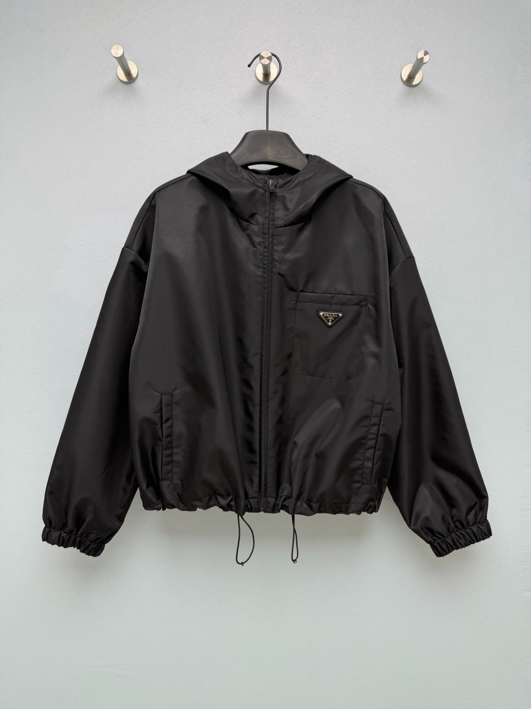 NO:950079,PRA* short hooded nylon jacket is made of the brand's classic recycled Re-Nylon nylon fabric with a matte and fine surface. It is windproof, water-repellent, lightweight and anti-wrinkle. The loose short version with dropped shoulders really makes the legs longer, and the waistline is directly raised, making it friendly to small people!  The drawstring hem, cuffs and hat can be tightened in many places throughout the body, so you can change the two styles at will. The iconic metal triangular nameplate is fixed with rivets on the left breast pocket, which is full of brand recognition, exquisite workmanship and wear-resistant. Multi-pocket practical structure, chest pocket + double side pockets, convenient storage of small items, smooth zippers are durable. Pure black basic color, versatile and easy to wear. Monochrome 4-code SMLXL, Prada-Clothing, prada, prada, jackets &  coats, hats,19860909PRA*短款连帽尼龙夹克 采用品牌经典再生Re-Nylon尼龙面料,表面哑光细腻,具备防风、防泼水、轻便抗皱特性.落肩宽松短版型真的巨显腿长,腰线直接拉高,小个子友好！ 全身多处可调节抽绳下摆、袖口、帽子都能收紧,两种风格随心换.标志性金属三角铭牌左胸口袋铆钉固定,品牌辨识度拉满,做工精致耐磨.多口袋实用结构,胸袋+双侧插袋,随身小物便捷收纳,顺滑拉链经久耐用.纯黑基础色调,百搭不挑穿搭. 单色4码 SMLXL,普拉达-服装,prada,prada,jackets & coats,hats,,Women's clothing