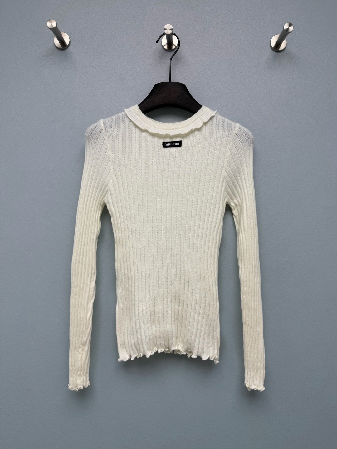 NO:950090,MIU* fungus edge pit strip slim fit knitted bottoming shirt  Fine pitted knitted fabric with clear texture, light and soft texture, moderate elasticity, breathable and skin-friendly. The neckline, hem, cuffs have fungus lace and soft and sweet lotus leaf curling details, weakening the monotony of knitting and filling up the exquisite atmosphere. Vertical stripes  The pitted weave with subtle hollow jacquards visually slims down and improves the breathability of the fabric. The black woven fabric label and small black and white contrasting logos are low-key embellishments to enhance the refined recognition. The overall off-white and milky white tone is clean and soft, and is versatile regardless of color!  Single color size 3 SML, Miu Miu-clothing, miumiu,19860909MIU*木耳边坑条修身针织打底衫 细坑条针织面料,肌理感清晰,质地轻薄软糯,带有适度弹力,透气亲肤.领口、下摆、袖口木耳边花边,柔和甜美的荷叶卷边细节,弱化针织的单调感,精致氛围感拉满.竖条坑条织法,带细微镂空提花,视觉上显瘦,同时提升面料透气度.黑色织唛布标,黑白撞色小标识,低调点缀,提升精致辨识度.整体米白奶白色调,干净柔和,百搭不挑色系！ 单色3码 SML,缪缪-服装,miumiu,,Women's clothing