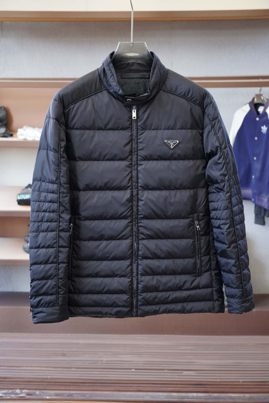 NO:600367,Prada - 2025 new autumn and winter products | Stand collar down jacket | Shows fashionable style. It does not follow the conventional design sense. The main body is made of imported fabric blends, environmentally friendly printing and dyeing, and the color is stronger and glossy. The front and back body are filled with large horizontal stripes and filled with 9010 white duck down. It is full and three-dimensional, meeting the needs of warm travel in autumn and winter.  The classic slightly wide cut and stand-up collar design create fashionable and high-end visual lines. The detailed three-dimensional triangle logo and zipper pockets make it easy to mix and match whether it is street style or fashion, showing a casual yet sophisticated dressing attitude. Color Black Size M-3XL, prada, down jacket, alexander wang19860909普拉达-2025 秋冬季新品｜立领羽绒服｜展现时尚风格  不据常规的设计感,大身采用进口面料混纺,环保印染更牢固色泽光感高级.前后身大幅横纹充绒工艺,9010白鸭绒填充,饱满立体,满足秋冬季保暖出行需求.  经典微阔裁剪,立领设计打造流行高级视觉线条.细节立体三角徽标,拉链口袋,无论是街头风格还是时装混搭,皆游刃有余,展现随性却不失精致的穿搭态度. 颜色黑色 尺码M-3XL,,prada,down jacket,alexander wang,Men's clothing