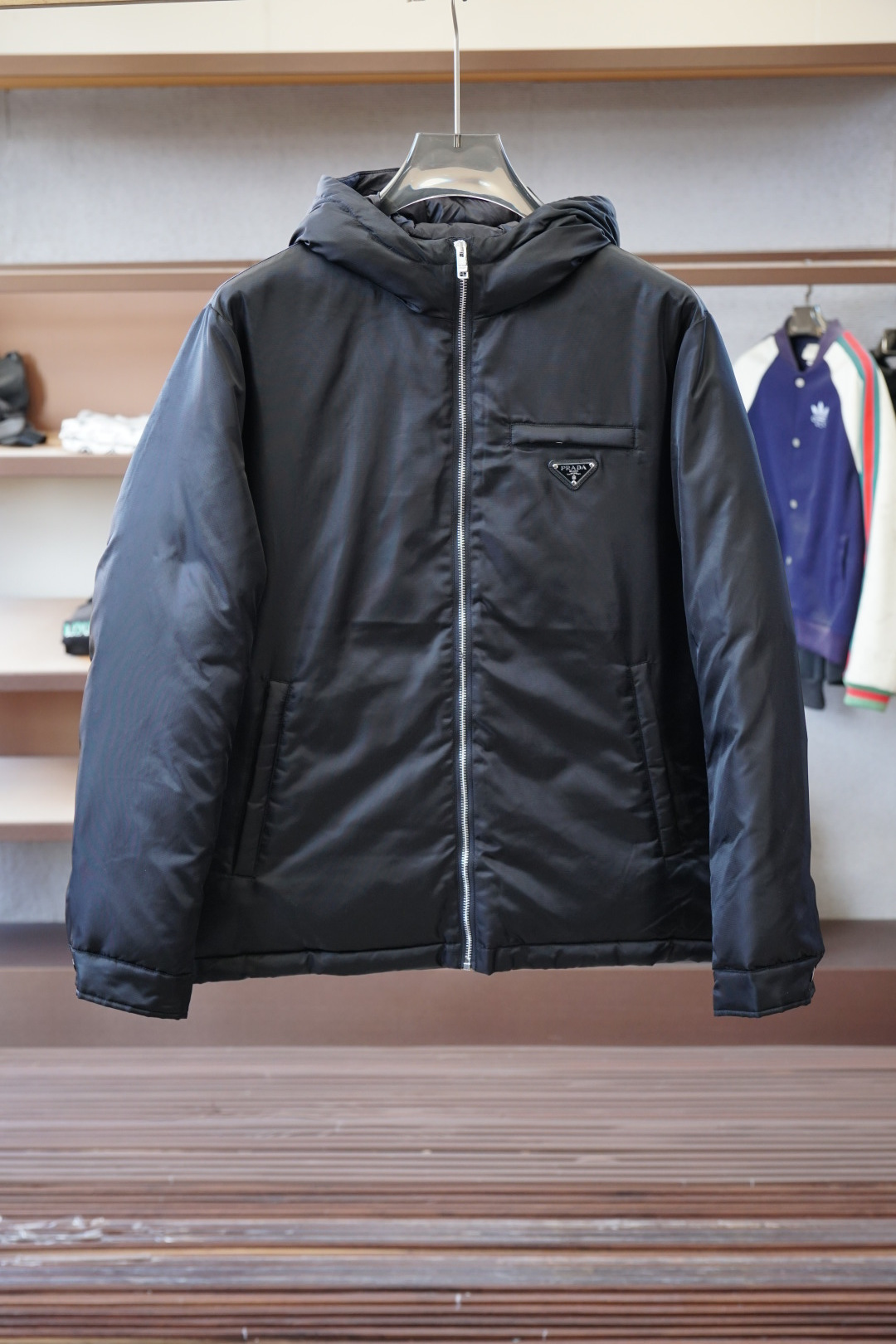 NO:600349,Prada-2025 New Products for Autumn and Winter｜Hooded Down Jacket｜Shows fashionable style. It does not follow the conventional design sense. The main body is made of imported fabric blends, and the environmentally friendly printing and dyeing makes the color more solid and glossy. The front and rear body are filled with large horizontal stripes and filled with 9010 white duck down. It is full and three-dimensional, meeting the needs of warm travel in autumn and winter.  The classic slightly wide cut and stand-up collar design create fashionable and high-end visual lines. The detailed three-dimensional triangle logo and zipper pockets make it easy to mix and match whether it is street style or fashion, showing a casual yet sophisticated dressing attitude. Color Black Size M-3XL, prada, down jacket, hats, alexander wang19860909普拉达-2025 秋冬季新品｜连帽羽绒服｜展现时尚风格  不据常规的设计感,大身采用进口面料混纺,环保印染更牢固色泽光感高级.前后身大幅横纹充绒工艺,9010白鸭绒填充,饱满立体,满足秋冬季保暖出行需求.  经典微阔裁剪,立领设计打造流行高级视觉线条.细节立体三角徽标,拉链口袋,无论是街头风格还是时装混搭,皆游刃有余,展现随性却不失精致的穿搭态度. 颜色黑色 尺码M-3XL,,prada,down jacket,hats,alexander wang,Men's clothing