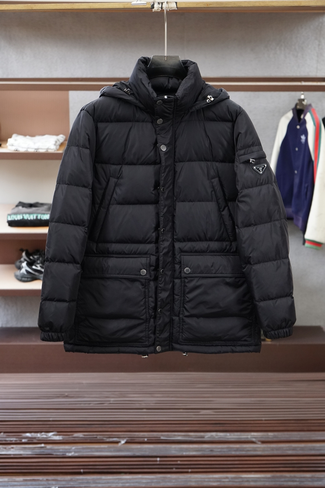 NO:625057,Prada-2025 New Products for Autumn and Winter｜Hooded Down Jacket｜Shows fashionable style. It does not follow the conventional design sense. The main body is made of imported fabric blends, and the environmentally friendly printing and dyeing makes the color more solid and glossy. The front and rear body are filled with large horizontal stripes and filled with 9010 white duck down. It is full and three-dimensional, meeting the needs of warm travel in autumn and winter.  The classic slightly wide cut and stand-up collar design create fashionable and high-end visual lines. The detailed three-dimensional triangle logo and zipper pockets make it easy to mix and match whether it is street style or fashion, showing a casual yet sophisticated dressing attitude. Color Black Size M-3XL, prada, down jacket, hats, alexander wang19860909普拉达-2025 秋冬季新品｜连帽羽绒服｜展现时尚风格  不据常规的设计感,大身采用进口面料混纺,环保印染更牢固色泽光感高级.前后身大幅横纹充绒工艺,9010白鸭绒填充,饱满立体,满足秋冬季保暖出行需求.  经典微阔裁剪,立领设计打造流行高级视觉线条.细节立体三角徽标,拉链口袋,无论是街头风格还是时装混搭,皆游刃有余,展现随性却不失精致的穿搭态度. 颜色黑色 尺码M-3XL,,prada,down jacket,hats,alexander wang,Men's clothing