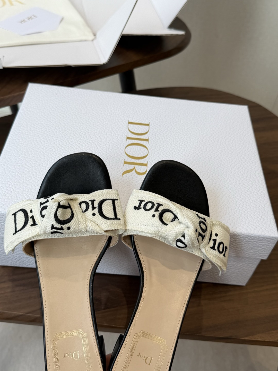Dior26ss夏季新款字母织带平底一字拖鞋这双拖鞋以品牌标志性的字母织带打造，搭配同色系的皮质鞋床，简