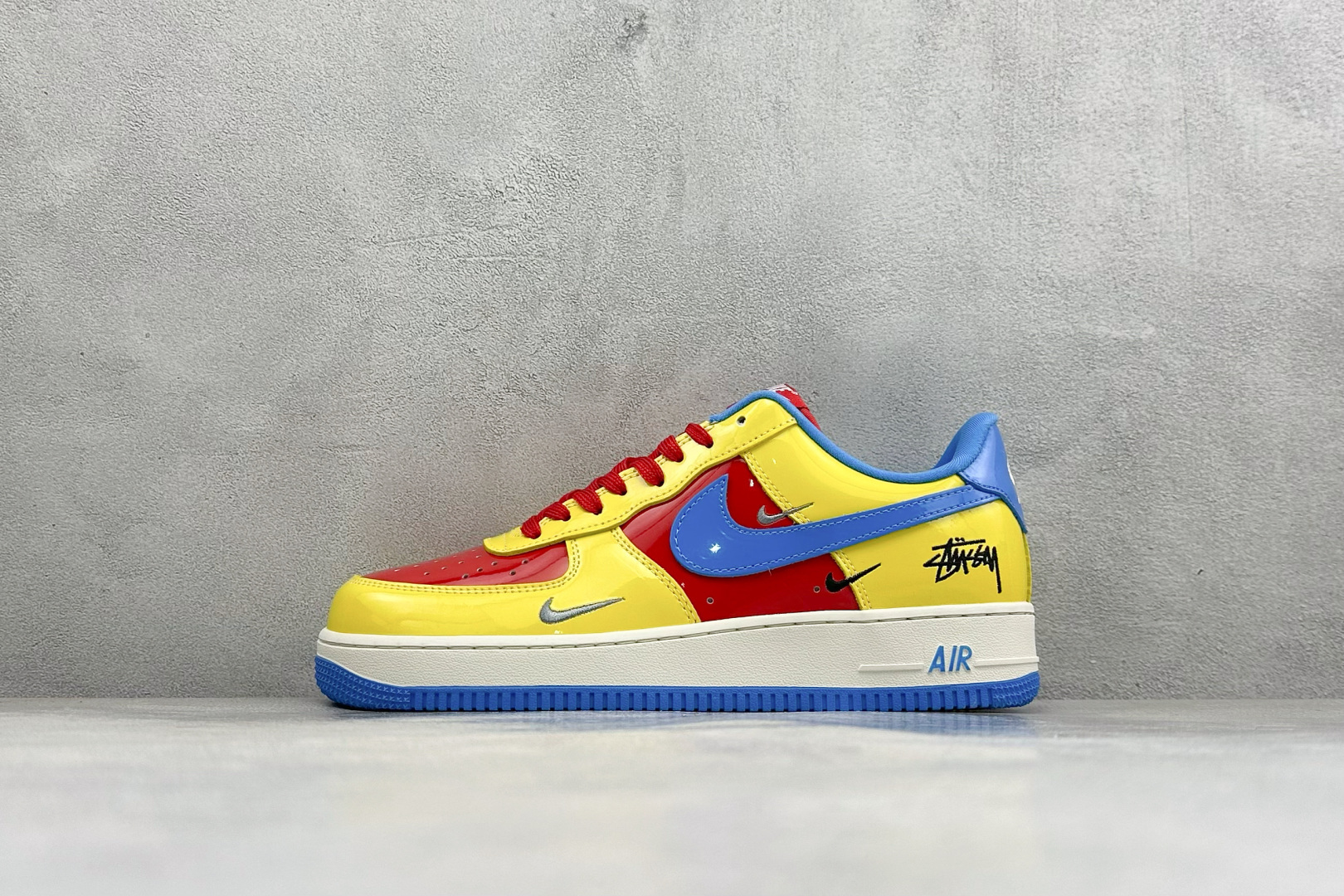 撞色潮玩 吸睛出圈 AIR FORCE 1，亮面漆皮打造红黄蓝三色拼接视觉，大小双勾错落排布搭配侧边斯图西签名印花，潮流