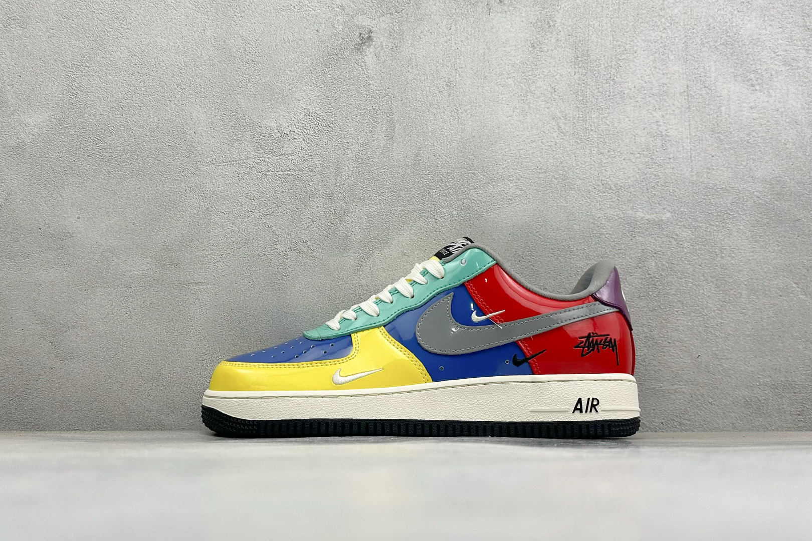潮色撞色吸睛出圈 AIR FORCE 1，这款斯图西联名空军一号采用亮面漆皮拼接打造多彩撞色鞋身，多层迷你Swoosh钩