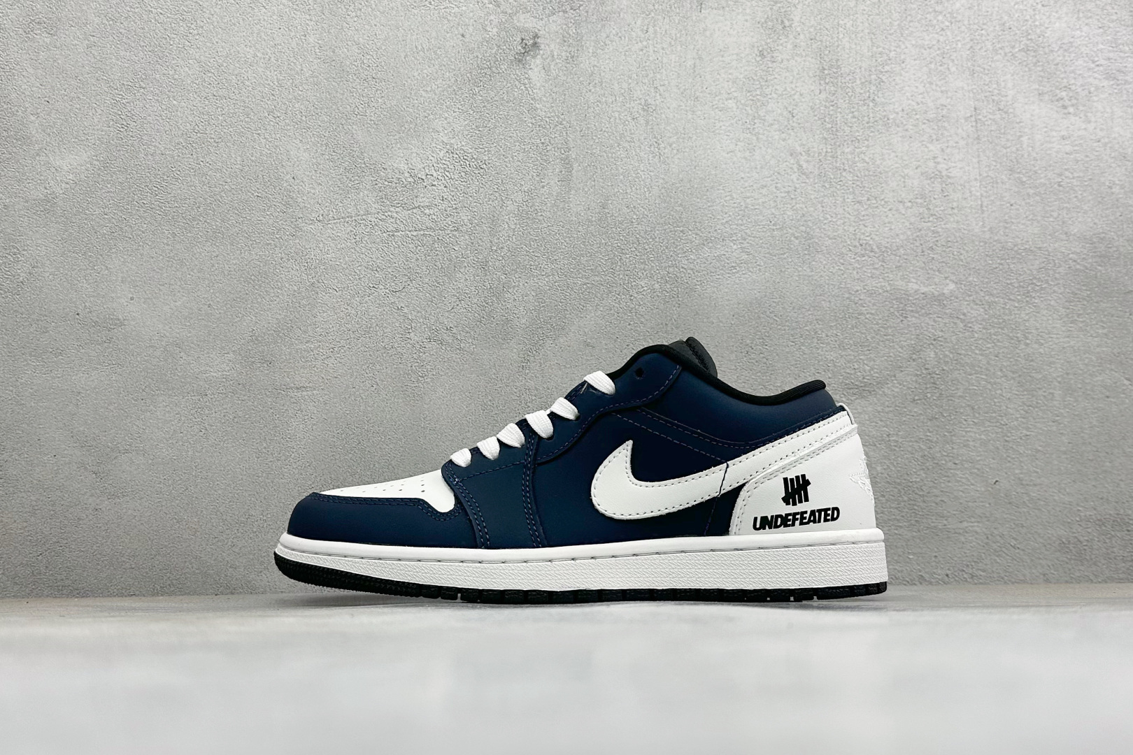 潮范出击 吸睛利器 AIR JORDAN 1，低帮AJ1藏蓝白撞色设计复古感拉满，利落皮革鞋面质感扎实，侧边印有UNDE