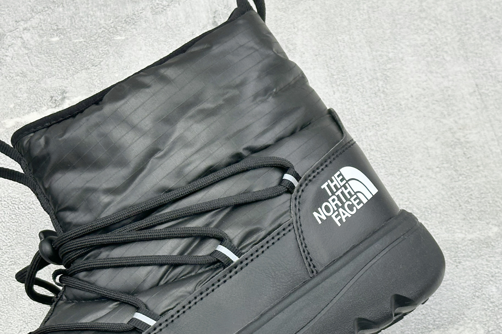 The North Face 北面高帮雪地靴，格纹尼龙防泼水面料，内里加厚绒毛，锁温保暖。快速抽绳锁扣设计，穿脱便捷，牢
