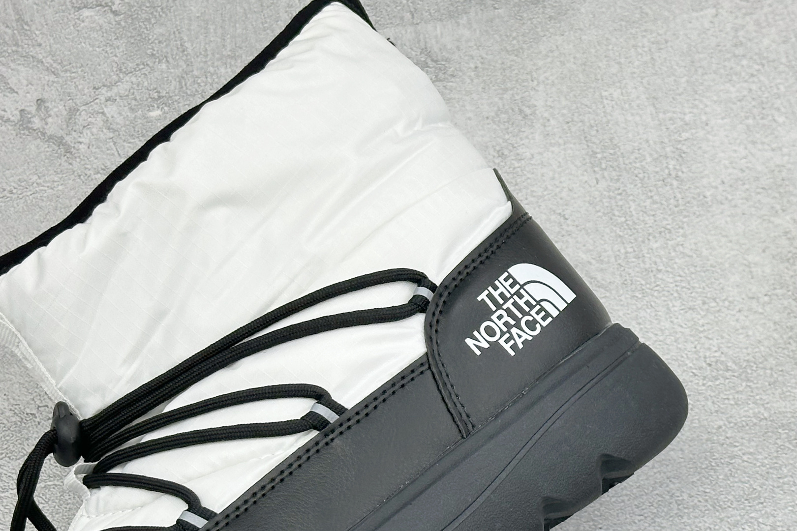 The North Face 北面高帮雪地靴，格纹尼龙防泼水面料，内里加厚绒毛，锁温保暖。快速抽绳锁扣设计，穿脱便捷，牢