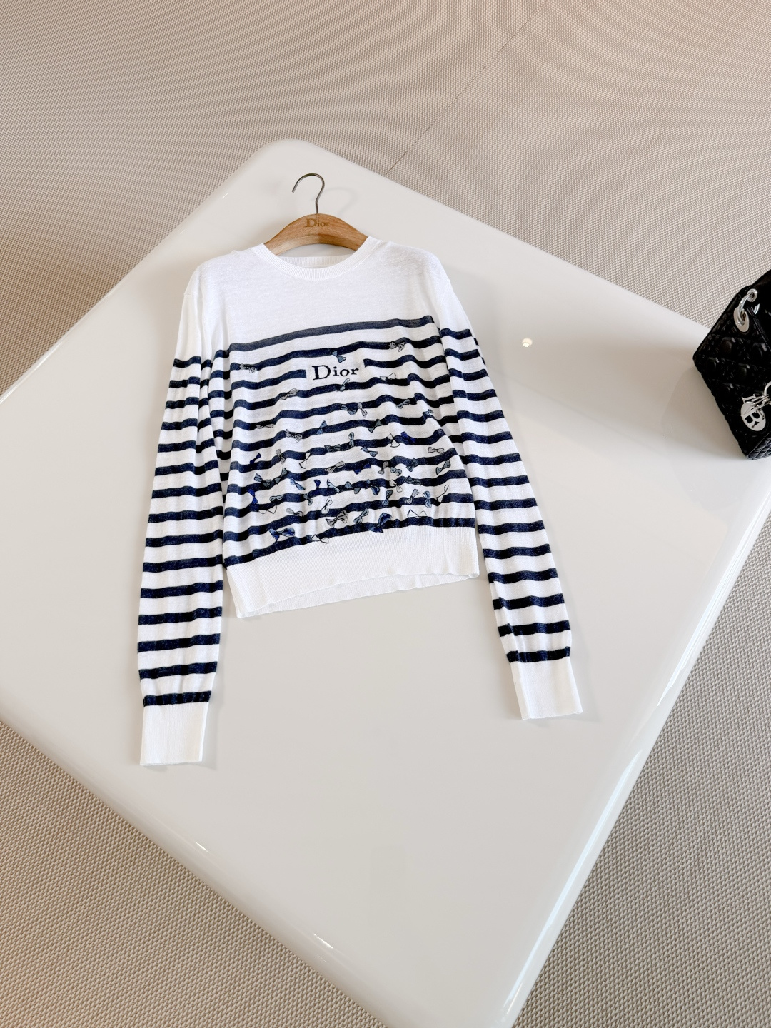 NO:841641,DIO 26S black and white color block striped bow printed pearl sweater. Crafted from white and navy blue blended knitted fabric. Decorated with blue Bows pattern and Anderson's signature bow. Regular fit. Decorated with brand logo on the front. Ribbed trims enhance the style.,dior,19860909DIO 26S 黑白拼色条纹蝴蝶结印花珍珠衫 采用白色和海军蓝色混纺针织面料精心制作 饰以蓝色Bows图案,安德森的特色蝴蝶结 常规版型 正面饰以品牌标志 点缀以罗纹饰边提升格调,,dior,,Women's clothing