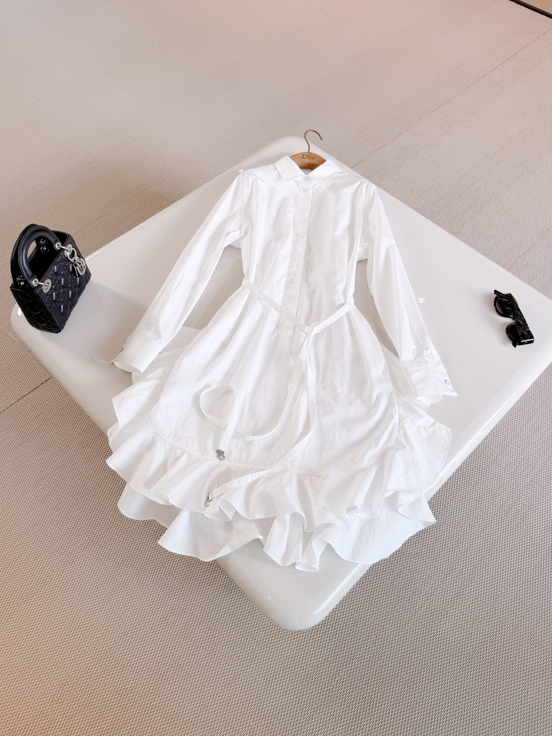 NO:841656,DIO 26S Asymmetric hem ruffled cotton belted dress. The mid-length is crafted from white cotton poplin. It has an elegant and sheer flared silhouette, with asymmetrical ruffles and a tone-on-tone belt. Decorated with a bow and silver-finish metal C and D initials to enhance the style, dior, skirts,19860909DIO 26S 不对称下摆荷叶边棉质腰带连衣裙 中长款采用白色棉府绸精心制作 呈现飘逸薄透的喇叭形廓形,搭配不对称荷叶边和同色调腰带 饰以蝴蝶结和银色饰面金属C和D首字母提升格调,,dior,skirts,,Women's clothing