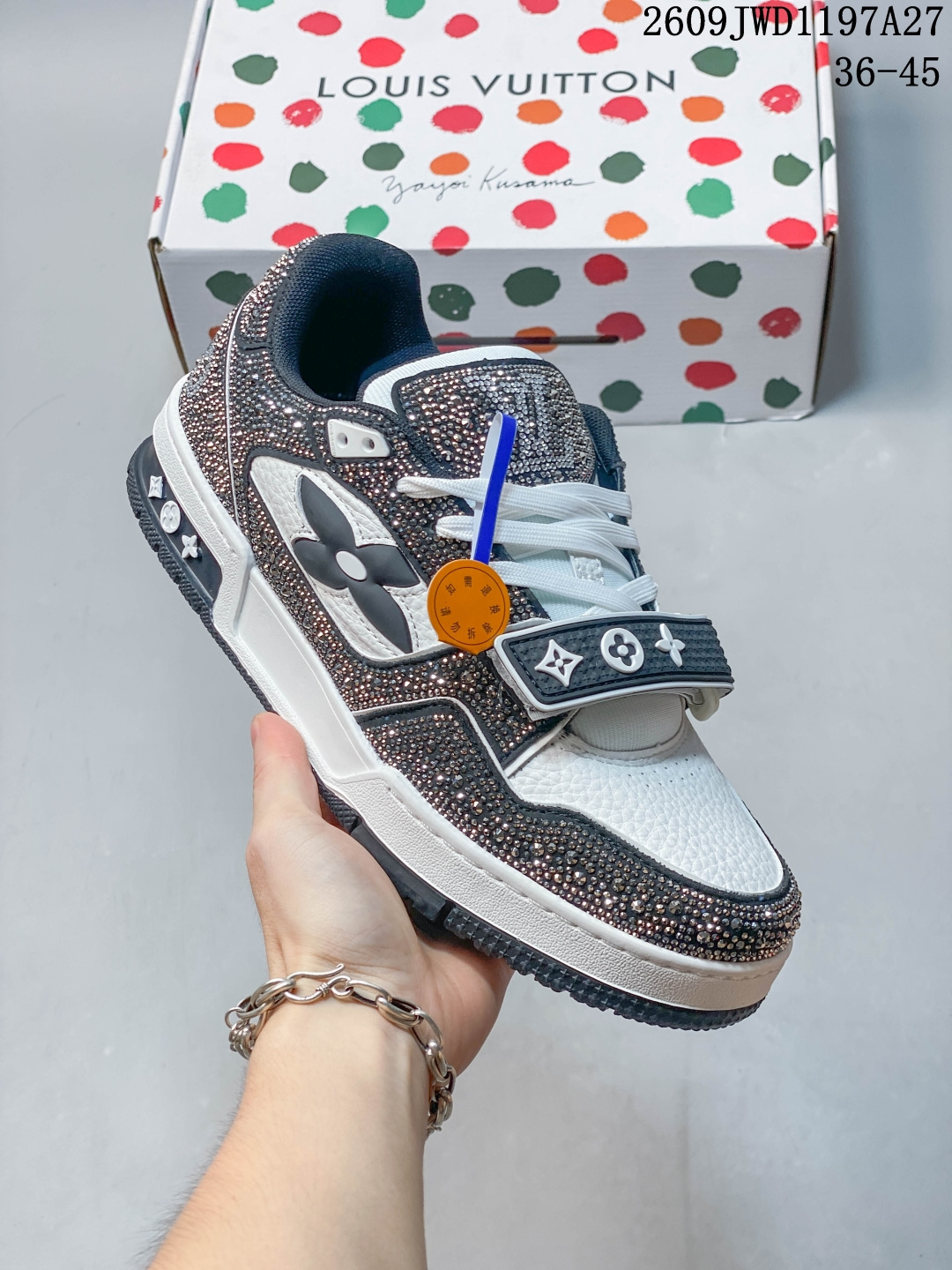 LV Trainer 草间弥生联名满钻魔术贴板鞋 奢潮限量款，满钻重工设计，自带高光，吸睛王者。 鞋面大面积手工镶嵌满钻，闪闪发亮，质感拉满。搭配荔枝纹牛皮拼接，经典老花标识，辨识度超高级。魔术贴 + 鞋带双设计，穿脱方便，可自由调节松紧。 复古篮球鞋轮廓，加厚橡胶中底，脚感舒适，轻微增高级。外底带有品牌经典花纹，防滑耐磨，扎实耐穿。 黑白撞色高耐看，满钻加持，聚会、出街、穿搭拍照巨出片。休闲裤、西装裤都能搭配，。 09JWD1197A27 image 1