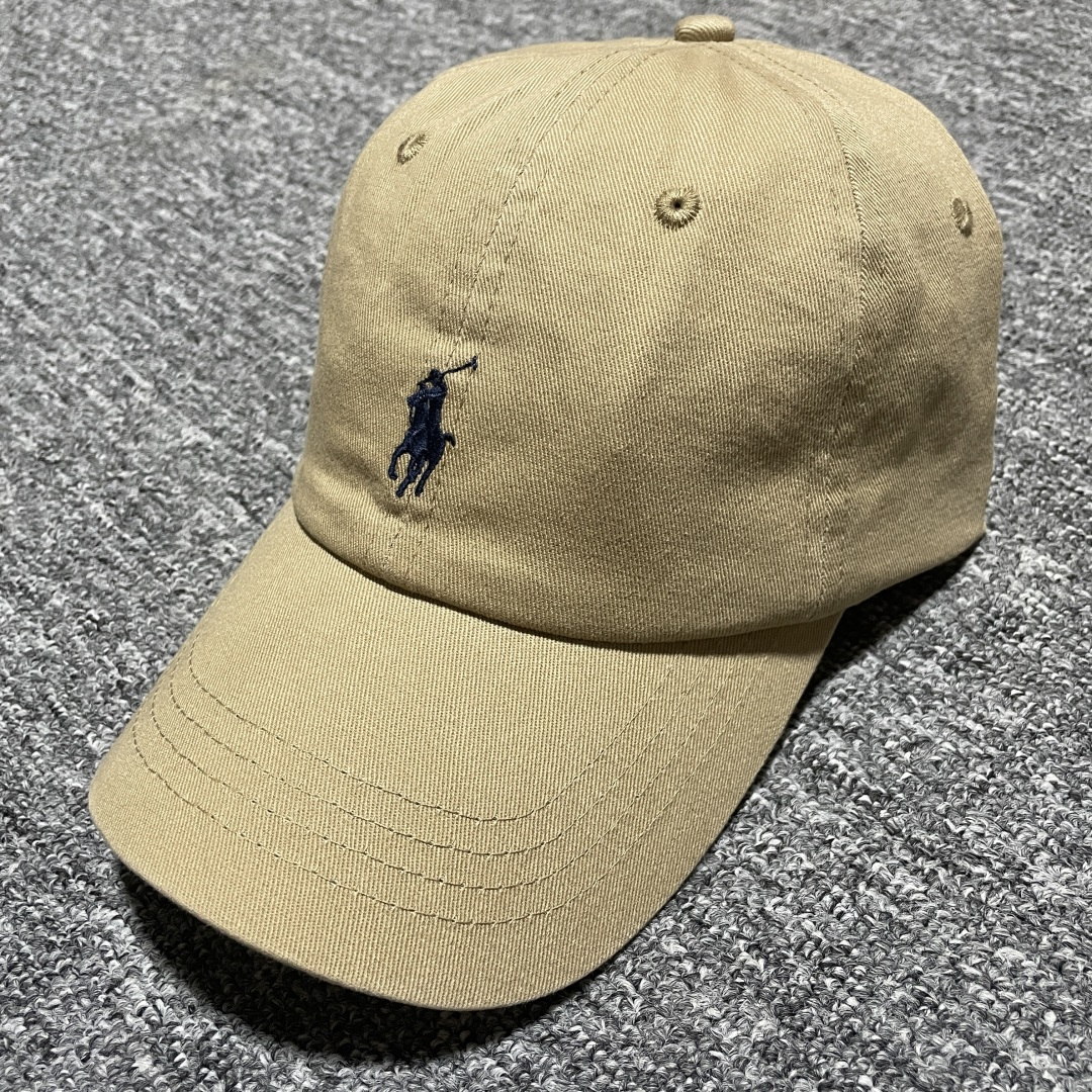 S# Ralph Lauren 拉夫劳伦 小马标 鸭舌帽 藏青/卡其 真正原版购回开发打版 高端零售专供 品质保证 100%放心出街 均码（52CM-62CM) 增礼佳品 ！附赠全套包装及定制手提袋 材质与工艺细节 主要材质 帽身： 采用高品质棉质帆（Cotton Twill）帆布材质紧密、硬挺有型，质感高级且耐磨 帽檐： 内部有内衬，采用轻质的聚合物板，使其能够轻松弯曲定形且不易折断，恢复性好 扣具： 金属按扣和棉质调节带，金属扣质感厚重，表面打磨光滑，刻有品牌Logo“Polo” 内里： 与头部接触的部分通常采用舒适吸汗的棉质或缎面材质，车线工整，不会有粗糙的线头 核心工艺细节： 刺绣工艺：清晰立体，标志性的Polo Player（马球手）Logo 或RL字母Logo 是核心，正品刺绣非常精致，针脚密集、均匀、饱满，图案边缘清晰锐利，无多余线头 色彩精准： 马球手的马鞍、马缰、球杆、衣服等不同部分的颜色区分清晰，即使是很小的细节也不会糊成一团 结构剪裁：帽身由6片面料拼接而成，拼接处的车线非常工整均匀，走线平直，弧度自然 定形工艺： 帽檐的弧度经过精心设计，既经典又现代。帽冠的弧线饱满，佩戴起来头型好看 重要鉴定点（真伪辨别） 假货（Fake）通常在以下细节上露出马脚 Logo刺绣 – 最重要的鉴定点 大货💯： 马球手Logo栩栩如生 马球杆： 球杆清晰可见，与手臂有区分 马腿： 至少能看到2-3条马腿的轮廓，线条分明 马鞍和马缰： 细节清晰，不会绣成一坨 整体比例： 马球手的身材比例协调，动作自然 市场版本❌： 刺绣粗糙、稀疏、扁平，马球杆可能看不清，马腿糊在一起，整体看起来呆板、畸形，充满廉价感 ！ 内部标签（Oxford Label） 真品材质： 通常是柔软的牛津布，质感好 印刷： 字体清晰、干净、粗细均匀“Ralph Lauren”字样精致-选品中心