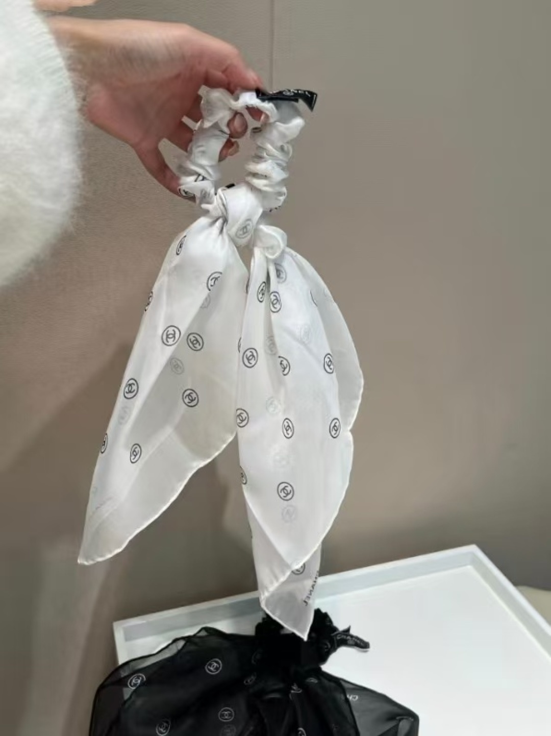 NO:921307,Chanel all-over printed square scarf hair tie two-in-one hair accessory. A Chanel treasure item, Chanel's two-in-one hair tie is clearly played. The thin and transparent full-print gauze fabric is very summery. The combination of large intestine hair tie and tulle square scarf has multiple uses: it is the simplest to use as a hair accessory. It can also be tied on the hands. Use a square scarf and a small hair tie to tie a bow and tie it behind a sun hat. It is sweet and cool.  Increase the sense of dressing. Use necklaces and rings to turn the hair tie into a halter neck tie, which can directly become a new accessory. Hang it on a shirt or make a unique necklace. It can be tied around the neck and tied behind as a choker, or it can be tied in the front. Size 53×53cm, material silk chiffon scarves, streamers, hair bundles, chanel, shirts, necklace, ring, real silk, ties, hats19860909香奈儿满印方巾发圈二合一发饰 一款香奈儿 的宝藏单品, 香奈儿 这个二合一发圈玩得明明白白的.薄薄透透的满印薄纱面料很夏天.大肠发圈和薄纱方巾的结合,一物多用: 用作发饰就是本来最简单的了.也可以绑手上.用方巾跟小发圈结合扎蝴蝶结绑在太阳帽后,甜酷本酷 增加穿搭感.用项链跟戒指可以把发圈变成挂脖领带,直接变成新的配饰,挂在衬衫上或者做单独特色的项链,可以绑脖子上后系当方巾choker,也可以前系.尺寸53×53cm,材质真丝雪纺丝巾,飘带，发束,chanel,shirts,necklace,ring,real silk,ties,hats,accessory