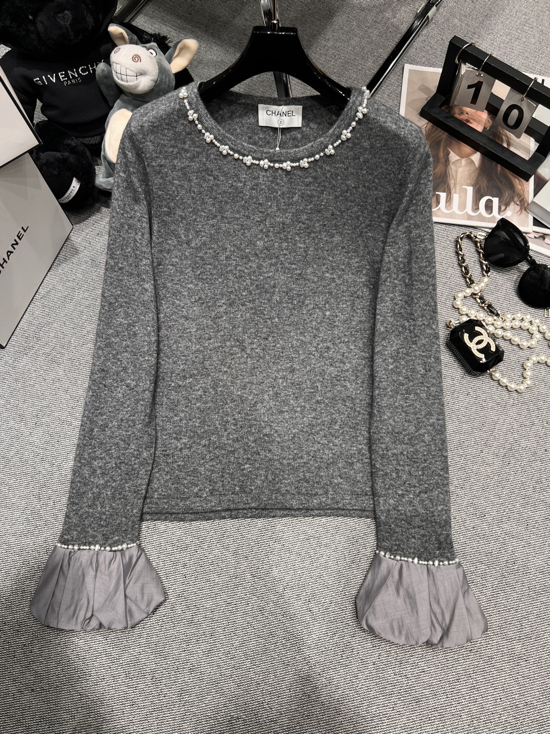 NO:549300,——CHANE*——2025 autumn and winter new knitted top. It adopts a round neck design, with pearl elements at the neckline, which is full of exquisiteness; the cuffs are trumpet-shaped, and pearls are also embellished, and light yarn fabric is spliced ​​to add a soft atmosphere. Chanel, alexander wang19860909——CHANE*——2025秋冬新款针织上衣.采用圆领设计,领口处珍珠元素,精致感十足；袖口为喇叭状,同样点缀珍珠,且拼接了轻盈的纱质面料,增添柔美气息,,chanel,alexander wang,Women's clothing