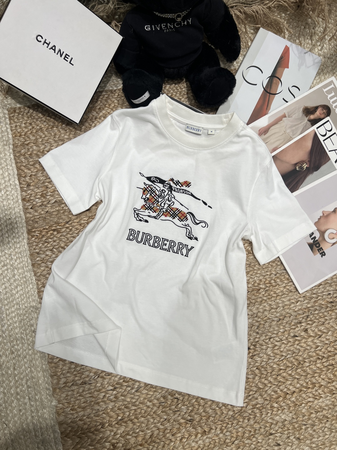 NO:830207,——Burber**——2026 SS sketch knight logo T-shirt, made of lightweight poplin cotton, comfortable and breathable to wear. The equestrian knight logo on the chest is embroidered with chain stitches, the sketch lines are super artistic, and the plaid details are low-key to show the brand's classics. The shape is neat, the shoulder design is available in white and pink, it is versatile and fashionable, and it is great whether worn alone or layered, and it is easy to create a British style look!  SML XL,Burberry-clothing,burberry,loro piana,tees,t-shirt,19860909——Burber**——2026年SS素描骑士徽标T恤,采用轻盈府绸棉,穿着舒适透气.胸前马术骑士徽标用链式缝线刺绣,素描线条感超有艺术气息,格纹细节低调展现品牌经典.版型利落,正肩设计,白色和粉色可选,百搭又时髦,无论单穿还是内搭都很出彩,轻松打造英伦风造型！SML XL,博柏利-服装,burberry,loro piana,tees，t-shirt,,Women's clothing