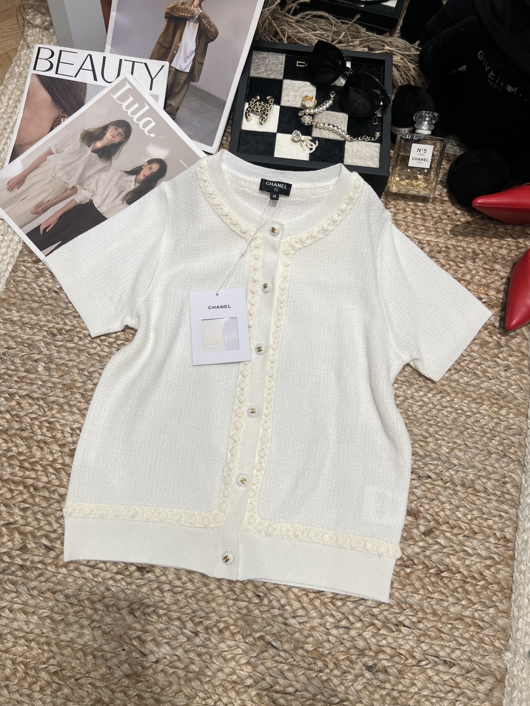 NO:892332,——Chane*——2026 SS white short-sleeved knitted cardigan, made of soft knitted fabric, with exquisite lace and metal buttons, full of details. The round neck design is simple and elegant, and the short sleeves are refreshing, perfect for spring and summer!  Lace decoration makes the whole thing more elegant, and can be easily used in daily life or light luxury occasions. Whether paired with wide-leg pants or skirts, it can show a gentle and noble temperament. It is a practical and fashionable versatile item~SML,,chanel,skirts,T-shirt,19860909——Chane*——2026年SS白色短袖针织开衫,采用柔软针织面料,搭配精致花边和金属纽扣,细节满分.圆领设计简约大方,短袖清爽,春夏穿超合适！花边装饰让整体更优雅,日常或轻奢场合都能轻松驾驭.无论搭配阔腿裤还是裙装,都能展现温柔贵气气质,是实用又时髦的百搭单品～SML,,chanel,skirts,T-shirt,,Women's clothing
