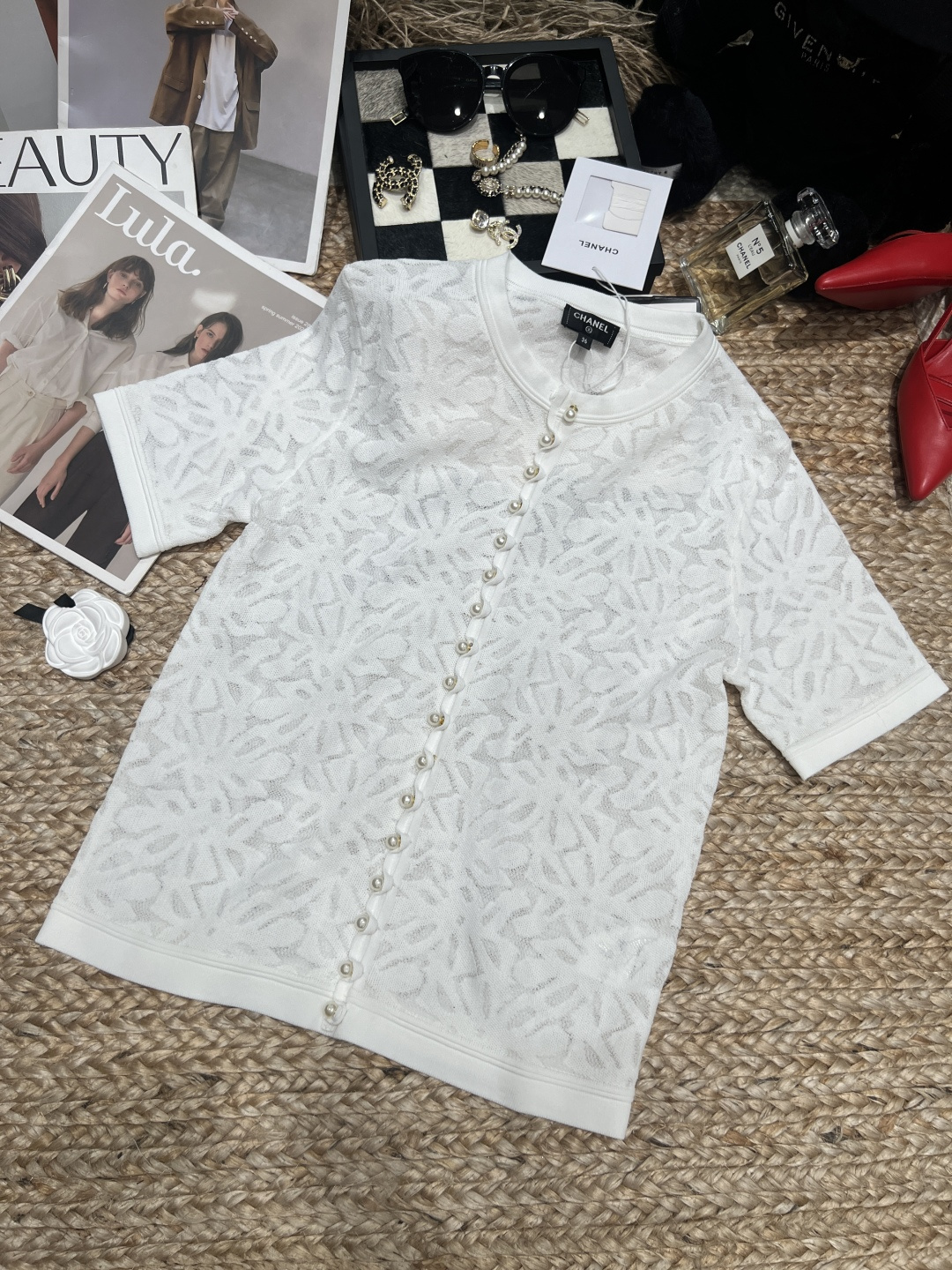 NO:892335,——Chane*——2026 SS white jacquard fabric pullover knitted top. The body is covered with exquisite plant textures and has a delicate texture. The round neck + pearl button design is elegant and detailed. The cut is loose, super comfortable to wear in spring and summer, and can be easily worn in daily or light formal occasions. Pair it with light-colored trousers or skirts, it is fresh and natural, and you can easily get your temperament!  SML,,chanel,skirts,19860909——Chane*——2026年SS白色提花面料套头针织上衣,衣身布满精致植物纹理,质感细腻,圆领+珍珠纽扣设计,典雅又有细节感.剪裁宽松,春夏穿超舒适,日常或轻正式场合都能轻松驾驭.搭配浅色裤装或裙装,清新自然,气质轻松get！SML,,chanel,skirts,,Women's clothing
