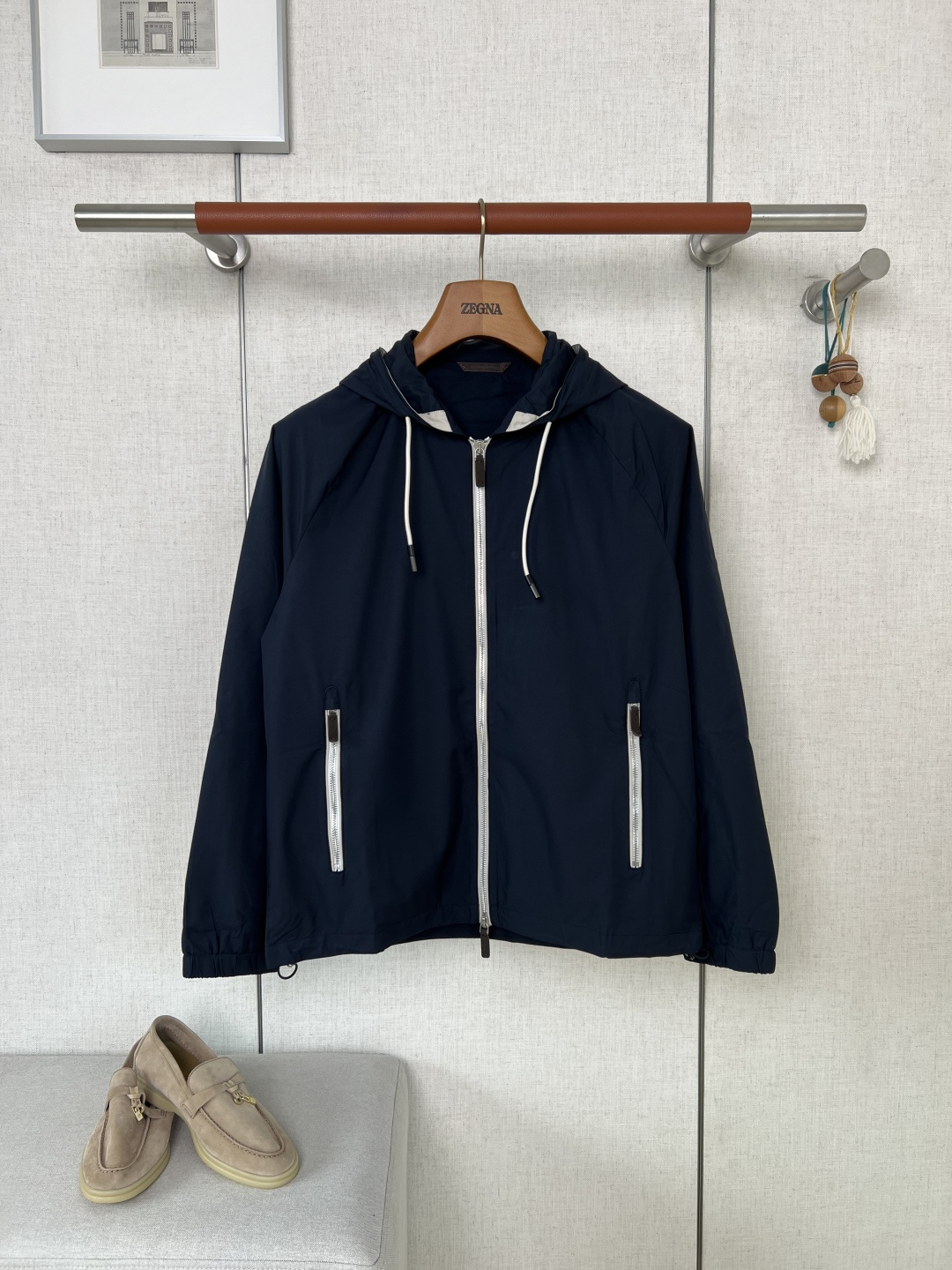 NO:957506,ZEGNA Navy blue hooded double zipper casual jacket #8872088  The brand's exclusive high-density functional windproof fabric is selected. The fabric feels delicate and crisp, with a low-key matte texture. The color fastness of the deep navy blue has been strictly controlled. It is not easy to fade and turn white when worn in daily wear. The fabric is light and breathable with good windproof and water-repellent properties. The upper body does not feel stuffy and sweaty. The fabric has its own shaping muscles and the upper body is not easy to collapse and wrinkle. It is suitable for daily commuting and short-distance travel.  The main placket adopts a recognizable double-open metal zipper, and the zipper accessories are matched with the brand's classic leather pull tags. The leather has been finely polished and feels warm to the touch. The sides of the zipper are edged with contrasting color webbing, so the zipper opens and closes smoothly without jamming, and there will be no problems with jams or teeth falling out. The storage pockets on both sides of the body use the same metal zippers with leather trims, and the zippers are surrounded by full-cover seams of the same fabric. Long-term use of the zipper corners will not scratch or wear the body fabric.  The inside of the body is made of precision overlock stitching. The stitches are arranged evenly and densely, without messy exposed floating threads. The seams are reinforced with double threads. Dark fabrics still have a high standard of stitching neatness, and the stitching color fits the garment.  The base color of the body means there will be no odd-colored jumpers or loose threads. If you reach out and rub the inside, you can intuitively feel the exquisiteness of the benchmark counter. The hood is equipped with an adjustable leather tail drawstring, and the lining of the hood is lined with contrasting colors to enhance sophistication; the hem  Equipped with a metal spring buckle drawstring system, the holes are reinforced, and the fabric can be pulled and adjusted repeatedly without tearing, and the hem can be tightened as needed to resist cold wind; the cuffs are elasticated and cut to fit the wrist to block wind intrusion; the overall style is a neat and slightly loose short cut without fancy printed logos, relying on the neat cut to interpret light and luxurious tones. The upper body has optimized shoulder and back lines, making it suitable for both business and casual wear scenarios, and is suitable for most adult men's styles.  The yarns on the surface of the fabric are densely and evenly arranged, and there is no problem of sparse yarns or local uneven thickness; all the pieces of the entire garment are cut strictly according to the original pattern, and the vertical height of the left and right pockets, the width of the body on both sides, and the length of the sleeves are controlled within a very small range, eliminating the common problems of piece misplacement, asymmetry of the left and right patterns, and uneven sleeve lengths that are common in the market. The symmetry of the entire garment is excellent.  The process of fabric color fixation, zipper accessories assembly, and multi-piece symmetrical cutting of dark-colored functional jackets has raised the bar for garment production. Defects in the fabric and substandard wiring will be directly scrapped, and the loss of raw materials has increased significantly. The hard-core workmanship has widened the texture gap between the affordable jackets on the market. Consumers who prefer low-key luxury men's clothing and value the workmanship of garments can easily distinguish the obvious difference in grade. Color Navy Size  48/50/52/54/56,,zegna,jackets & coats,jackets & coats,hats,19860909ZEGNA杰尼亚藏青色连帽双拉链休闲夹克  #8872088 甄选品牌专属高密机能防风面料,面料触感细腻挺括,自带低调哑光肌理,深藏青色色牢度经过严格把控,日常穿搭不易掉色泛白,面料兼顾轻薄透气性与不错的防风抗泼水属性,上身不闷汗,布料自带定型筋骨,上身不易软塌起皱,日常通勤、短途出行都能适配 主门襟采用辨识度双开金属拉链,拉链配饰搭配品牌经典真皮拉牌,皮料经过细腻打磨触感温润；拉链侧边做撞色织带包边处理,拉链开合顺滑不卡顿,不会出现卡布、掉齿问题；身前两侧储物口袋沿用同款真皮饰件金属拉链,拉链周边做同面料全包缝锁边,长期使用拉链边角不会刮蹭磨损衣身面料. 衣身内里全域做精密包缝走线各处针脚排布均匀密实,无杂乱外露浮线头,接缝位置做双线补强加固.深色面料对针脚工整度依旧高标准把控,缝线色调贴合衣身底色,不会出现异色跳线、松散线头,伸手摩挲内里可以直观感受到对标专柜的细腻做连帽搭配可调节皮质尾端抽绳,帽口内衬做撞色包边提升精致度；下摆配备金属弹簧扣抽绳系统,孔位做加固处理,反复拉扯调节不会撕裂面料,可按需收紧下摆抵御冷风；袖口做松紧收口剪裁,能够贴合手腕阻挡风灌入；整体版型是利落微宽松短款剪裁,没有花哨印花logo,依托利落剪裁诠释轻奢调性,上身优化肩背线条,商务休闲穿搭场景都适配,适配多数成年男士穿搭风格. 面料表层纱线排布致密均匀,不存在纱线稀疏、局部厚薄不一的问题；整件衣服全部裁片严格对标原版版型裁切,左右口袋垂直高度、两侧衣身宽度、袖长长短误差控制在极小范围,杜绝市面通货普遍存在的裁片错位、左右版型不对称、袖子长短不齐的通病,整件成衣裁片对称度表现优异 深色机能夹克在面料固色、拉链辅料装配、多裁片对称裁剪几道工序拉高了成衣制作门槛,面料瑕疵、车工走线不达标都会直接做报废处理,原料损耗大幅提升,硬核做工拉开和市面平价外套的质感差距,偏爱低调轻奢男装、看重成衣做工质感的消费者,能轻松分辨出品级上的明显差别 颜色 藏青色 尺码 48/50/52/54/56,,zegna,jackets & coats,jackets & coats,hats,,Men's clothing