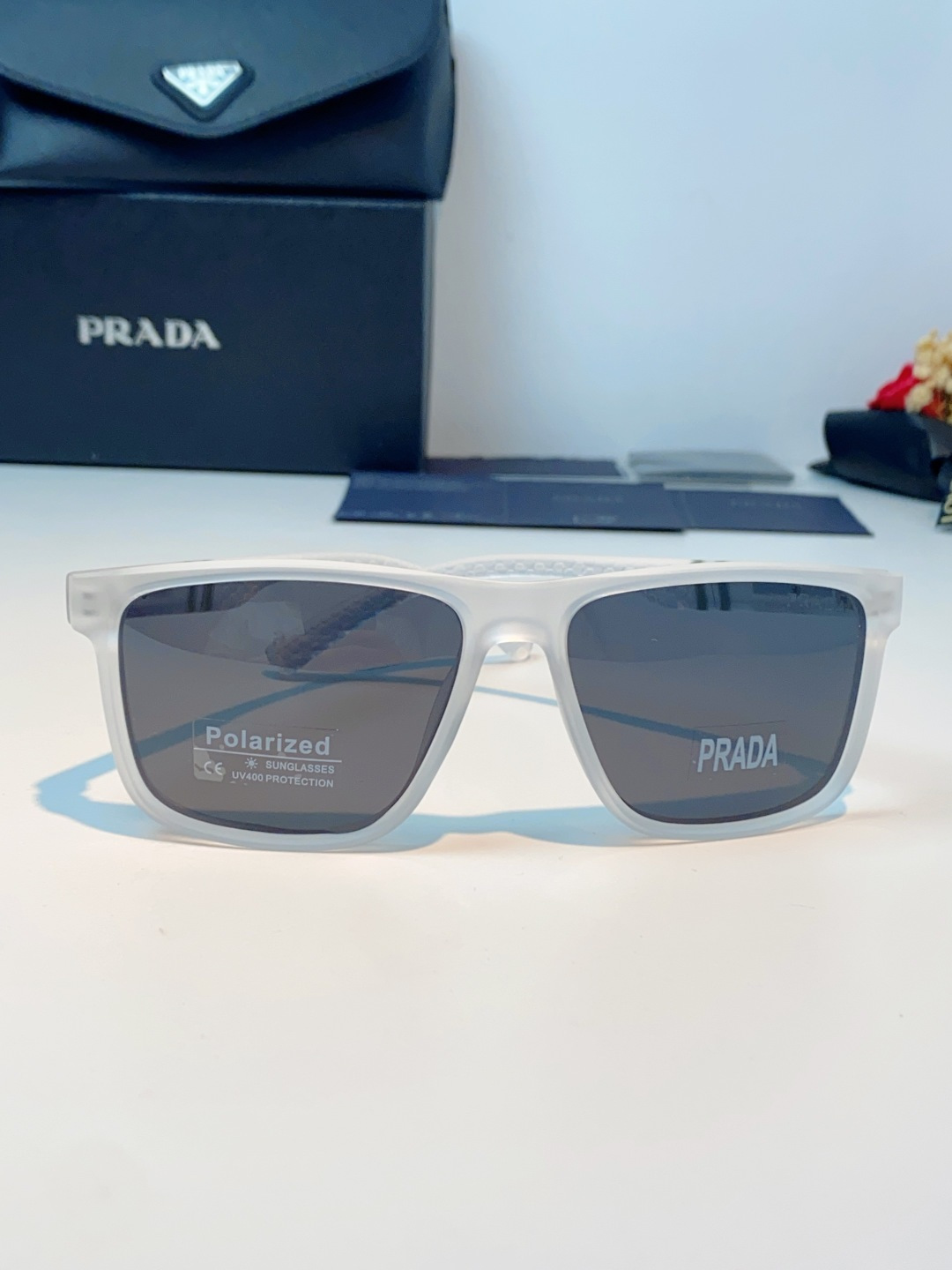Prada普拉达 男士偏光太阳镜，经典方型镜框设计，哑光/亮面质感镜架搭配标志性红标，低调彰显品牌辨识度