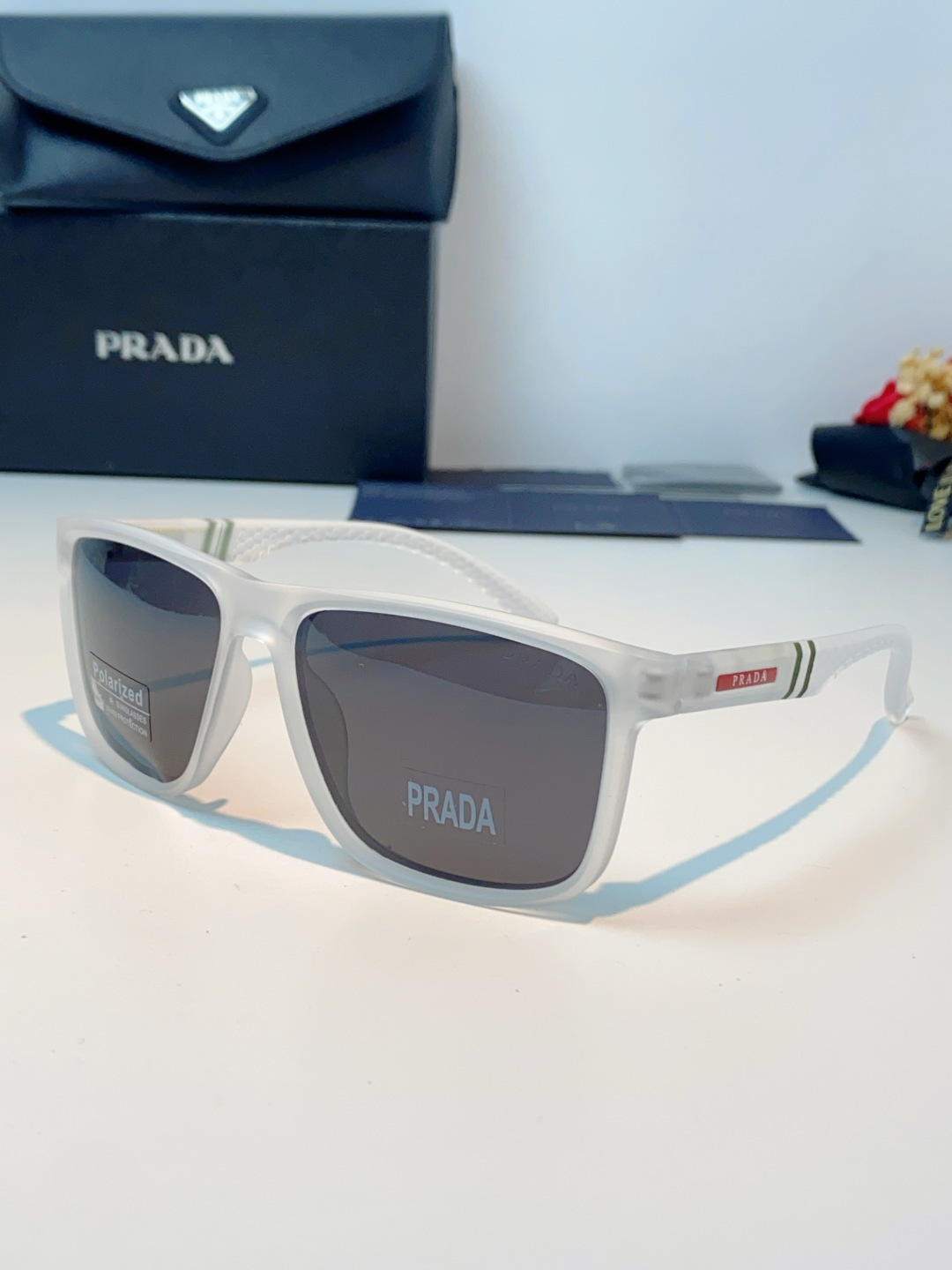 Prada普拉达 男士偏光太阳镜，经典方型镜框设计，哑光/亮面质感镜架搭配标志性红标，低调彰显品牌辨识度