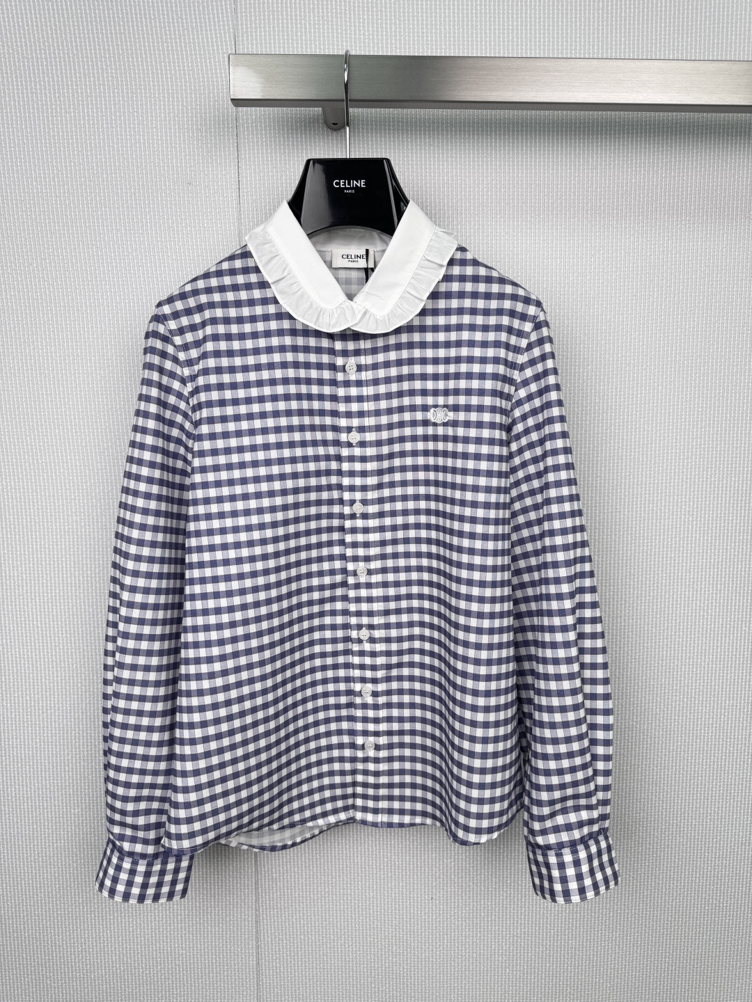 NO:577064,Celine's 2025 new autumn and winter baby collar plaid shirt, when the blue and white plaid meets the lotus leaf baby collar, every line is like the breeze blowing by the Seine River, the white buttons are like pearl embellishments, and the CELINE embroidery on the chest quietly tells the brand gene. This shirt hides the laziness and sophistication of a Parisian girl, the latte fragrance in the cafe in the morning, the light and shadow play in the art gallery in the afternoon, a shirt can easily control multiple scenes, and is smart and neat when commuting.  Gentle and calm when dating, a versatile tool in the wardrobe, selected breathable cotton fabrics, delicate plaid texture and three-dimensional ruffle tailoring, the details bear witness to the ingenuity and persistence of luxury goods. Pair it with white straight pants, and you will instantly become an artistic girl on the left bank. Pair it with a small black suit, and your workplace aura will be upgraded elegantly. Size SML,,celine,shirts,business suit,alexander wang19860909Celine2025秋冬新款娃娃领格纹衬衣,当蓝白格纹遇上荷叶娃娃领,每一道线条都是塞纳河畔拂过的微风,白色纽扣如珍珠点缀,胸前的CELINE刺绣悄然诉说品牌基因,这件衬衫藏着巴黎少女的慵懒与精致,清晨咖啡馆的拿铁香,午后美术馆的光影游戏,一件衬衫轻松驾驭多种场景,通勤时干练利落 约会时温柔恬淡,衣橱里的万能搭配利器,精选透气棉质面料,细腻格纹肌理遇见立体荷叶边剪裁,细节处见证奢侈品的匠心执着,搭配白色直筒裤,秒变左岸文艺女孩,外搭黑色小西装,职场气场优雅升级. 码数SML,,celine,shirts,business suit,alexander wang,Women's clothing
