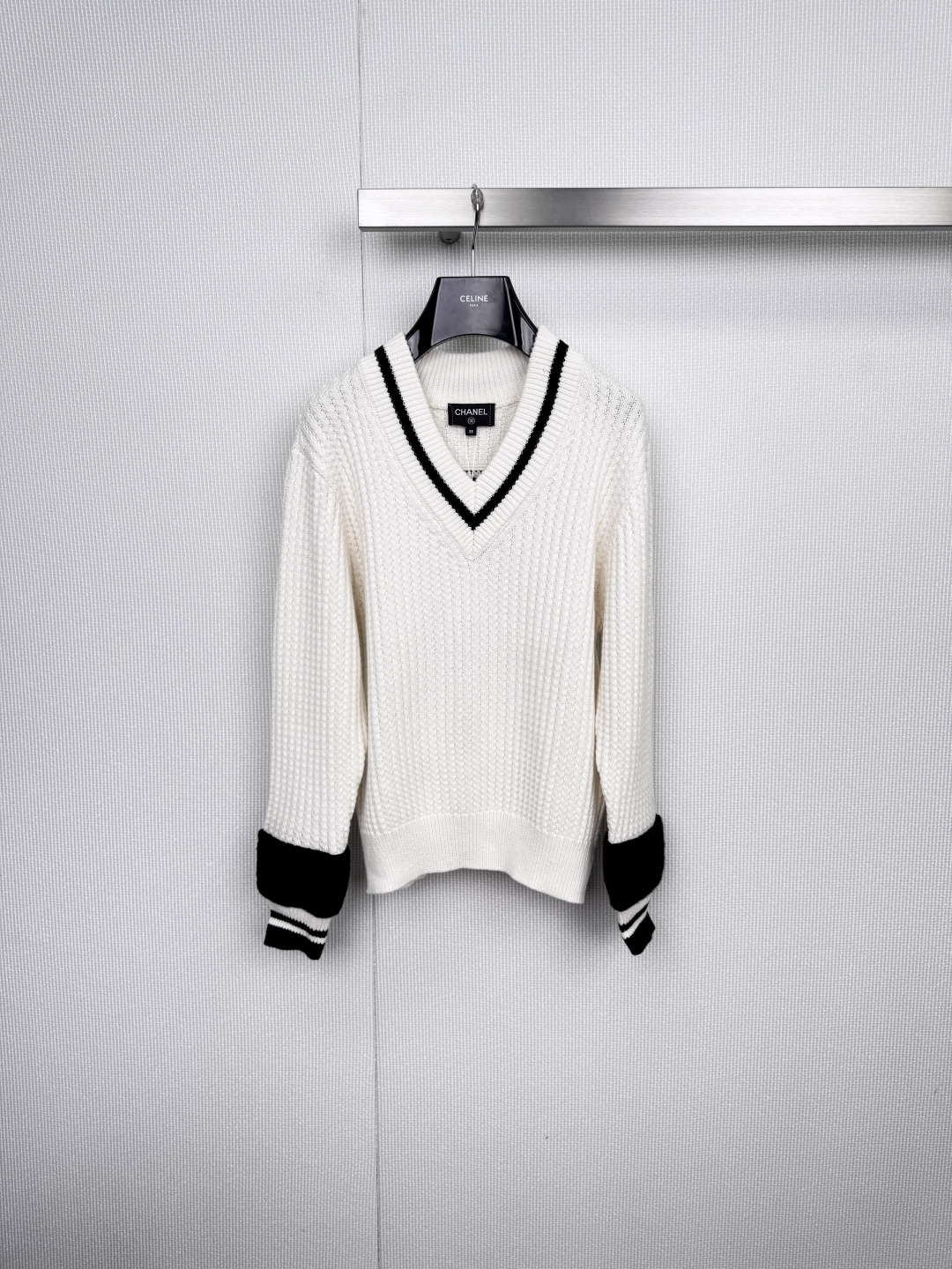 NO:578798,Chanel's 2925 new autumn and winter V-neck cardigan is elegant to the core and calm to the soul. It outlines minimalist aesthetics with classic black and white. This Chanel  The V-neck cardigan is made of pure white. The V-neck cut cleverly extends the neck line, making it look slimmer and unobtrusive. The cuffs are decorated with black stripes, echoing the metal buttons, and the details are high-end. Pair it with black plaid shorts from the same series, and a white chain bag slung across the body. The necklace is light between the collarbones.  Swaying, the overall laziness reveals French sophistication. Whether leaning against the warm wooden wall or in the mottled light and shadow of the green chair, it can sublimate daily scenes into fashion pictorials. It does not deliberately follow the trend, but always stays at the forefront of style - this is the power of Chanel's design language.  Code number SML,,chanel,shorts,necklace,alexander wang19860909Chanel 2925秋冬新款V领开衫,优雅入骨,从容入魂,以经典黑白勾勒极简美学,这件Chanel V领开衫以纯净白色为底,V领剪裁巧妙延伸颈部线条,显瘦不张扬.袖口点缀黑色条纹拼接,与金属纽扣呼应,细节处见高级质感,搭配同系列黑色格纹短裤,斜挎一支白色链条包,项链于锁骨间轻盈摇曳,整体慵懒中透出法式精致,无论是倚靠温润木墙,或置身绿椅斑驳的光影间,它都能让日常场景升华为时尚画报,不刻意追赶潮流,却始终游走于风格前沿——这就是Chanel设计语言的力量. 码数SML,,chanel,shorts,necklace,alexander wang,Women's clothing