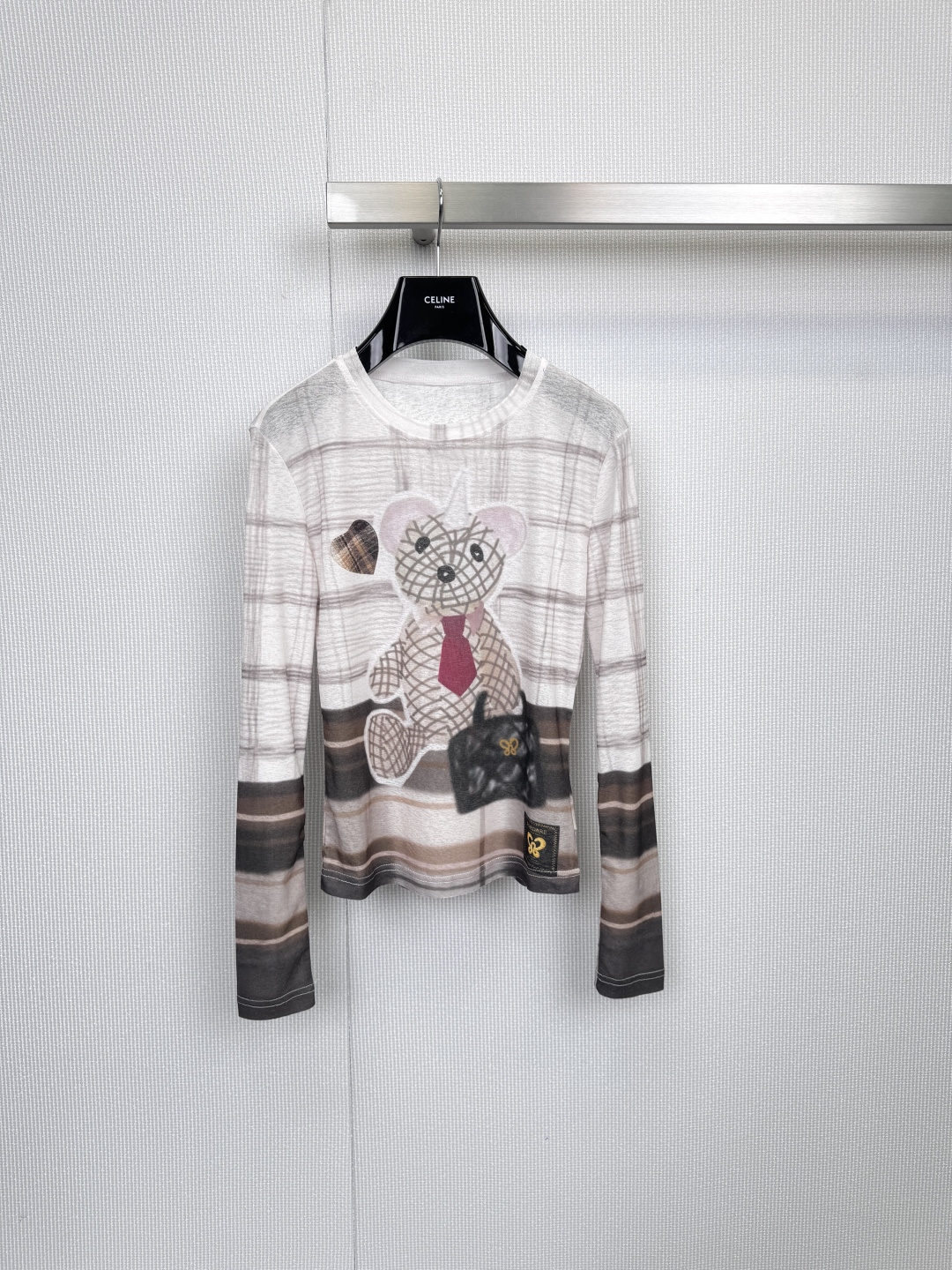 NO:589670,Vitality college style Fordare  Bear emblem striped long-sleeved bottoming shirt. Encountering this little bear wearing a red tie and carrying a small black bag will instantly make your daily wear full of story. Fordare's long-sleeved bottoming shirt is based on classic white and blends  It has a delicate plaid pattern, with contrasting stripes on the cuffs and hem. The details are perfect, and you can easily wear a fresh and energetic college style. The protagonist on the chest is a delicately dressed bear, embellished with a red tie and a black handbag, with a heart shape.  The plaid badge is cute and fashionable, instantly breaking the monotony. The cuffs and hem are edged with dark and light stripes, which not only enhances the layering of the design, but also brings a neat silhouette effect. The whole dress is covered with subtle plaid dark patterns, which makes the texture perfect when viewed up close. Say goodbye to the monotony of solid colors and improve the sophistication of the overall match. Whether you wear a shirt with the collar exposed, or wear a denim vest or vest outside, you can easily create the highlight of your outfit and become your must-have item for age reduction in spring and autumn!  Size SML,,shirts,ties,alexander wang19860909元气学院风Fordare 小熊徽章条纹长袖打底衫,邂逅这只系着红色领带、手拎小黑包的小熊,让你的日常穿搭瞬间充满故事感,Fordare这款长袖打底衫,以经典白色为底,融入细腻格子图案,袖口与下摆点缀撞色条纹,细节满分,轻松穿出清新活力的学院风尚,胸前主角是一只穿着精致的小熊,红色领带与黑色手提包点缀,搭配心形格子徽章,可爱又时髦,瞬间打破单调,袖口与衣摆采用深浅双色条纹收边,不仅增强设计层次感,更带来利落的版型效果,全衣布满细微的格子暗纹,近看质感满分,告别纯色单调,提升整体搭配的精致度,无论是内搭衬衫露出领口,还是外穿牛仔背心或马甲,都能轻松塑造穿搭亮点,成为你春秋季节的减龄必备单品！码数SML,,shirts,ties,alexander wang,Women's clothing