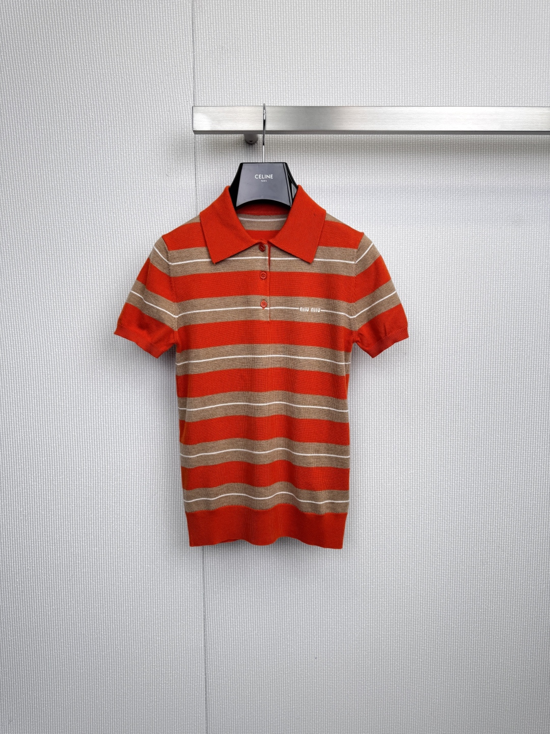 NO:590502,MiuMiu knitted short-sleeve is retro and playful, with red-brown and white stripes, as if the afterglow of the setting sun is shining into the clothes. This knitted short-sleeve has a classic Polo collar design to outline the dual texture of youth and elegance. Several red buttons are embellished in it, playful and jumping like candy, instantly lighting up the overall look. The white embroidered logo on the left chest low-key highlights the brand genes, and the details are exquisite. The soft knitted fabric fits the body shape but is not too tight.  Whether it is paired with high-waisted shorts to create a retro sports style, or paired with a white skirt to create a college atmosphere, it can be easily mastered in various scenes. The red and brown warmth collides with the pure white stripes, exuding just the right sense of vitality and luxury. From afternoon cafes to weekend parties, this short-sleeved piece is not only an easy wearer in the wardrobe, but also a secret weapon that inadvertently reveals good taste. Let Miu Miu’s unique girly feel accompany you to write this romantic chapter in winter!  Size SML,,miumiu,skirts,shorts,T-shirt,alexander wang19860909MiuMiu针织短袖复古俏皮,红棕与白色条纹相间,仿佛落日余晖洒入衣间,这件针织短袖以经典Polo领设计勾勒出青春与优雅的双重质感,几颗红色纽扣点缀其间,如糖果般俏皮跳跃,瞬间点亮整体造型,左胸处白色刺绣徽标低调彰显品牌基因,细节处尽显精致,柔软针织面料贴合身形,却不过分紧绷,无论是搭配高腰短裤打造复古运动风,还是配以白色半裙演绎学院气息,都能轻松驾驭多种场景,红棕暖意与纯净白条纹碰撞,散发恰到好处的活力与高级感,从午后咖啡馆到周末派对,这件短袖既是衣橱里的轻松担当,也是不经意间透露好品味的秘密武器,让缪缪的独特少女感,陪你书写这个冬日的浪漫章节吧！码数SML,,miumiu,skirts,shorts,T-shirt,alexander wang,Women's clothing